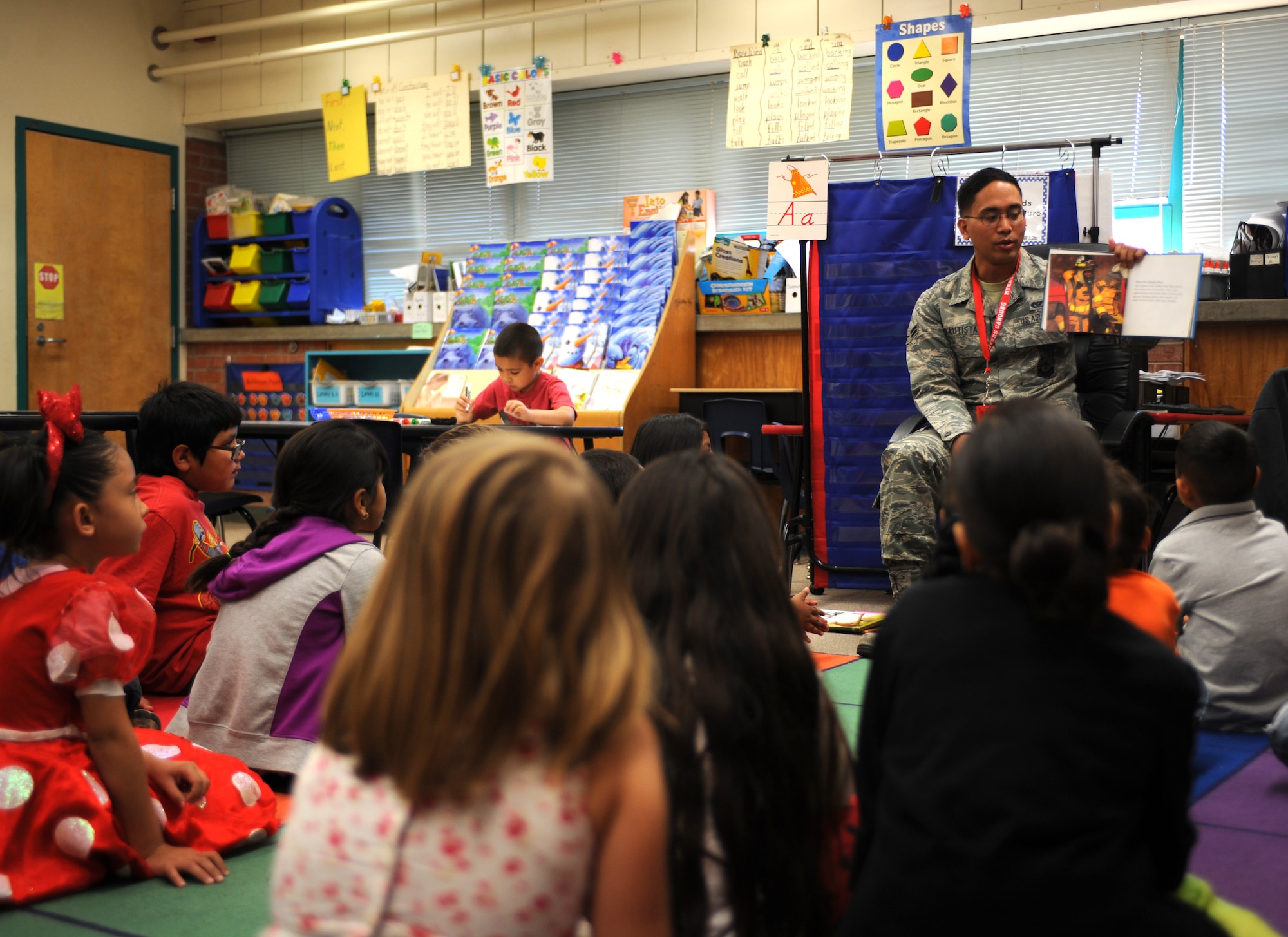 U.S. Air Force Airman 1st Class Jonathan Bautista, 355th Civil Engineer Squadron firefighter, reads to a 1st-grade class at Myers-Ganoung Elementary School in Tucson, Ariz., Feb. 12, 2014. Bautista volunteered his off-duty time to participate in Love of Reading Week, a week-long event that gives community members the opportunity to read stories to children during school. (U.S. Air Force photo by Airman 1st Class Cheyenne Morigeau/ Released)