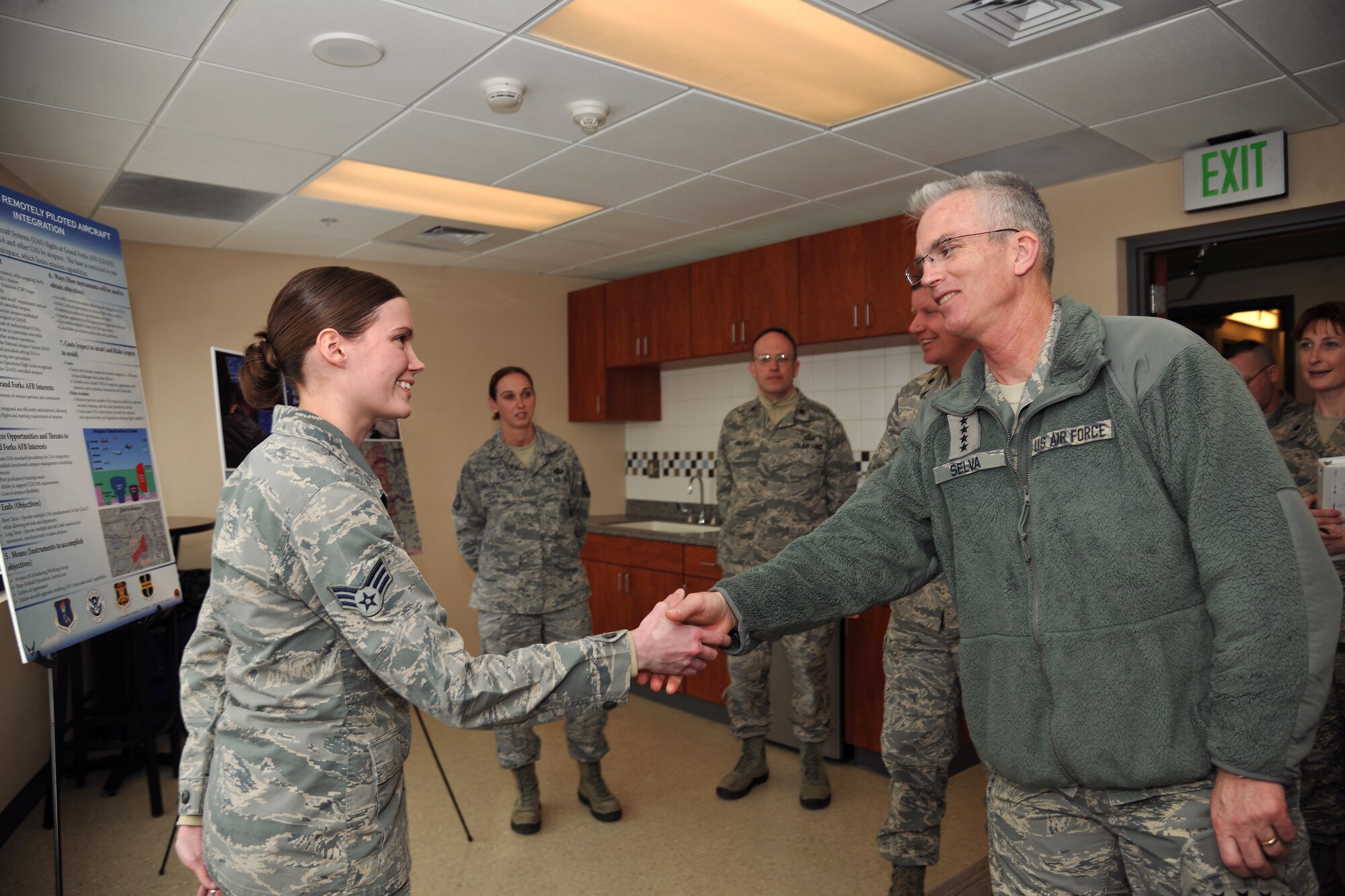 Senior Airman Elizabeth Boyette(left), 319th Operations Support Squadron air traffic controller radar approach and control, greets Gen. Paul Selva, Air Mobility Command commander(right), Feb. 11, 2014, on Grand Forks Air Force Base, N.D. Boyette briefed how the 319th OSS provides for the mission was part of the first day of the two-day tour (U.S. Air Force photo/Senior Airman Xavier Navarro)