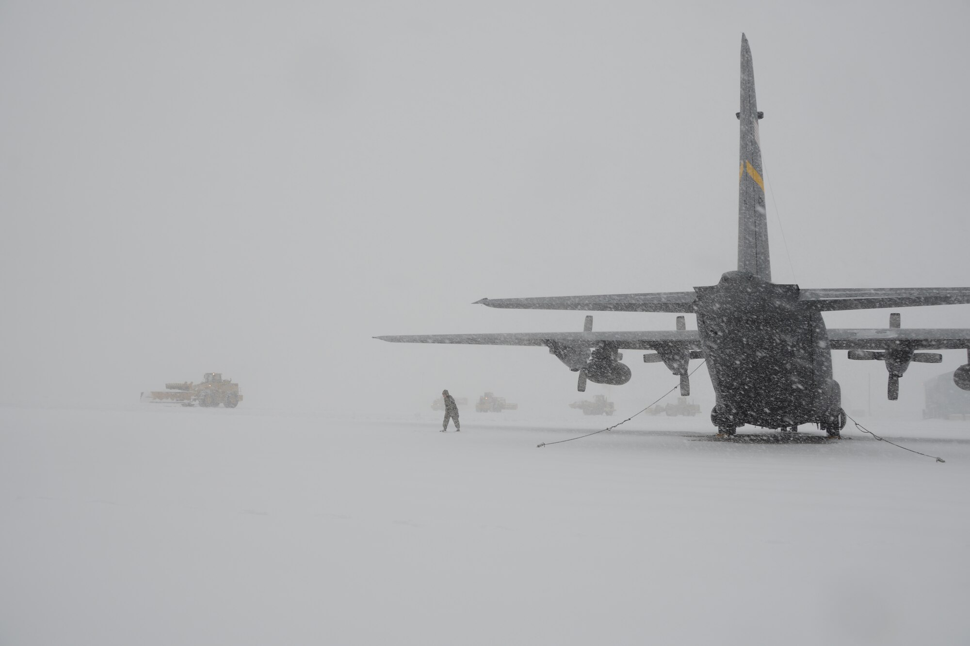 A lone Airman walks on the flightline near a C-130H aircraft assigned to the 103rd Airlift Wing at Bradley Air National Guard Base, East Granby, Conn., as plows work to clear the area of the rapidly accumulating snow from a nor’easter Feb. 13, 2014. More than 200 Airmen reported to work here and at the Orange Air National Guard Station, ready to answer the call in the event the state required assistance during the height of the storm.  (U.S. Air National Guard photo by Maj. Bryon M. Turner)