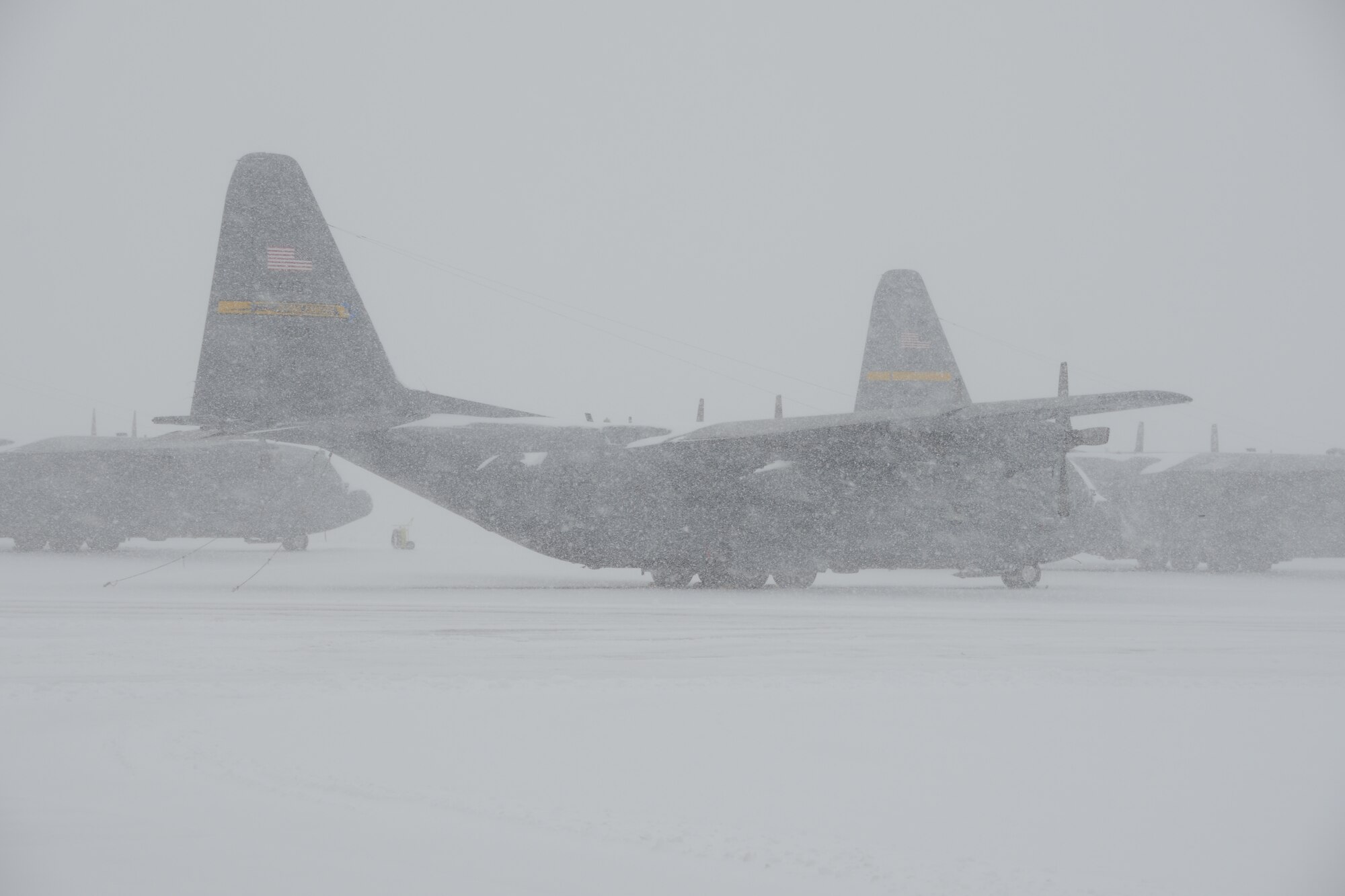 Three C-130H aircraft assigned to the 103rd Airlift Wing weather the storm during near whiteout conditions at Bradley Air National Guard Base, East Granby, Conn., as crews work to clear the flightline of the rapidly accumulating snow from a nor’easter Feb. 13, 2014. More than 200 Airmen reported to work here and at the Orange Air National Guard Station, ready to answer the call in the event the state required assistance during the height of the storm.  (U.S. Air National Guard photo by Maj. Bryon M. Turner)