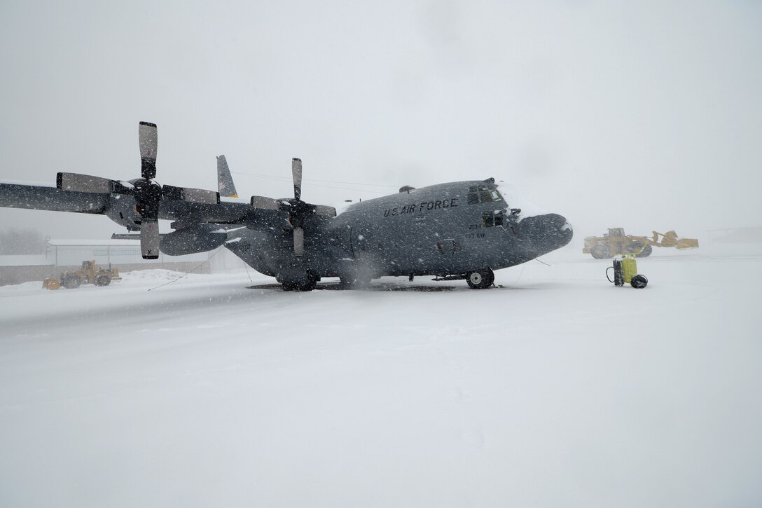 A C-130H assigned to the 103rd Airlift Wing in East Granby, Conn. weathers the storm Feb. 13, 2014, as more than a half dozen machines from the adjacent Bradley International Airport work to clear the rapdily accumulating snow from the aircraft ramp at Bradley Air National Guard Base, East Granby, Conn.  (U.S. Air National Guard photo by Master Sgt. Erin McNamara)