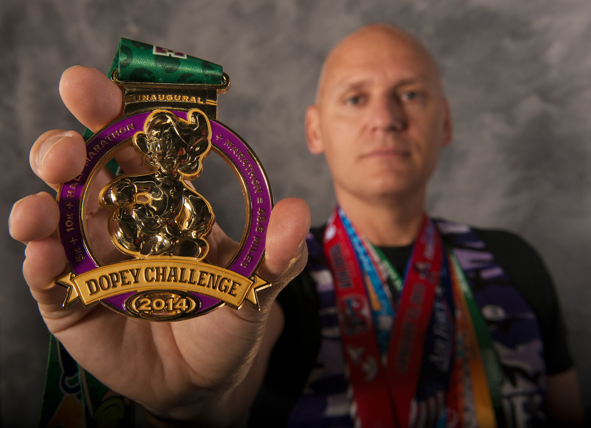 U.S. Air Force Chief Master Sgt. John Huhn, 723d Aircraft Maintenance Squadron superintendent, holds out his medal from the 2014 Dopey Challenge at Moody Air Force Base, Ga., Feb. 11, 2014. The Dopey Challenge, hosted at Walt Disney World, Fla., was a four-day race that progressed in length each day from a 5k, 10k, half marathon and finally ending with a full marathon on the last day for a grand total of 48.6 miles. (U.S. Air Force photo by Senior Airman Tiffany M. Grigg/Released) 