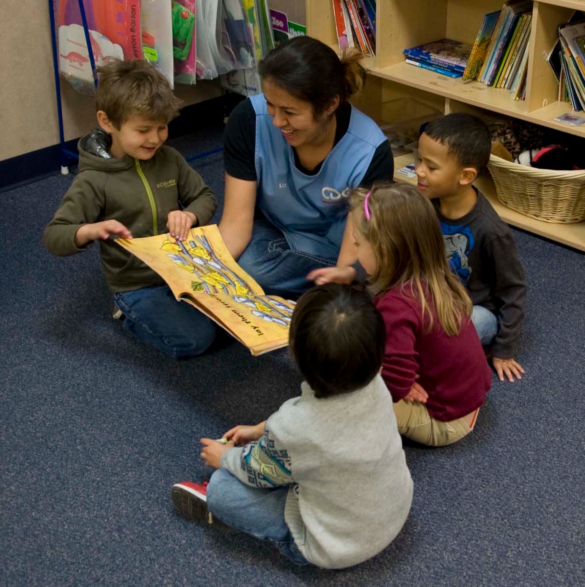 Liz La Rosa, Dyess Child Development Center caregiver, reads to a group of children Feb. 5, 2014, at Dyess Air Force Base, Texas.  La Rosa is one of many staff members that influence the positive relationships between parents and caregivers. The CDC has been awarded best in Air Combat Command for their Child Development Program for a second straight year.  (U.S. Air Force photo by Airman 1st Class Kylsee Wisseman/Released) 