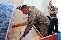 Staff Sgt. Nathan Richards, 39th Civil Engineer Squadron unaccompanied housing manager inspects a bed during a final-out dorm inspection Feb. 13, 2014, Incirlik Air Base, Turkey.  Col. Craig Wills, 39th Air Base Wing commander and Chief Master Sgt. Anthony Johnson, 39th ABW command chief experienced the daily duties of Airmen from the unaccompanied housing office on Incirlik AB. (U.S. Air Force photo by Airman 1st Class Nicole Sikorski/Released)
