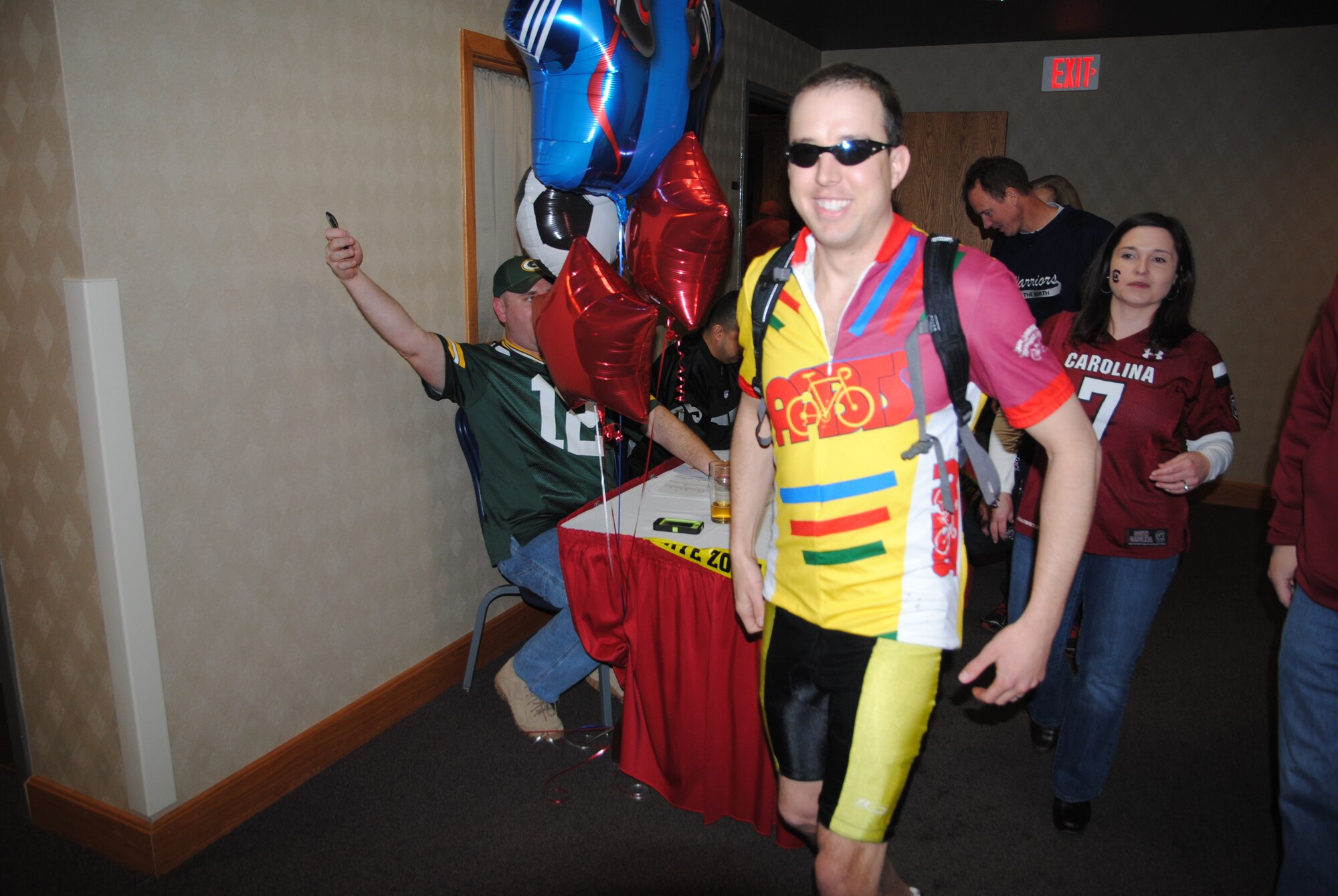 Wearing a bicyclist’s outfit, 1st Lt. Jon Datsko makes his way to his seat prior to the start of the 2013 Grand Forks Air Force Base Annual Awards Feb. 7, 2014, at the Northern Lights Club on Grand Forks AFB, N.D. The 2013 Annual Awards featured a sports theme and allowed quests to wear sport jerseys, caps and other athletic sports gear instead of the customary Air Force dress blues uniform. (U.S. Air Force photo/Staff Sgt. Luis Loza Gutierrez) 