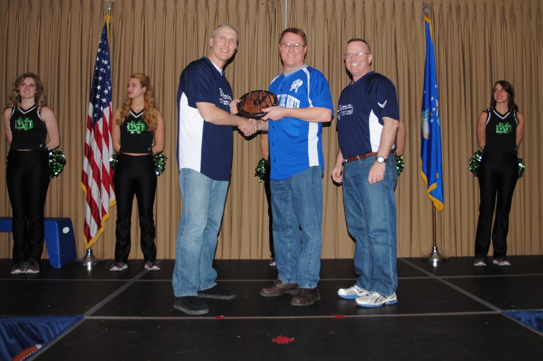 (At opposite ends) Col. Paul Bauman, 319th Air Base Wing commander and 319th ABW command chief, Chief Master Sgt. David Duncan, present Graham Pritchett, 319th Mission Support Group, with the award for the Category III Civilian of the Year category during the 2013 Grand Forks Air Force Base Annual Awards Feb. 7, 2014, at the Northern Lights Club on Grand Forks AFB, N.D. The 2013 winners received small Viking-style shields. (U.S. Air Force photo/Staff Sgt. Luis Loza Gutierrez)