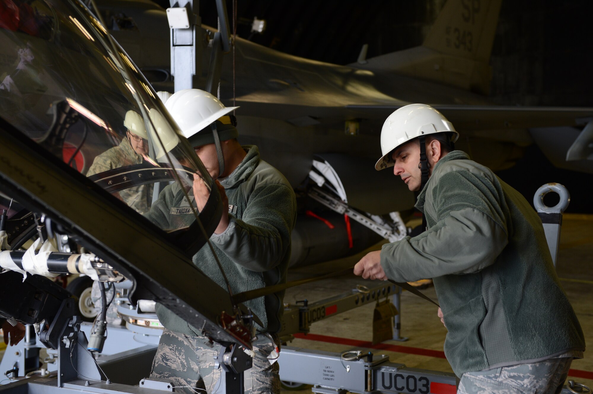 U.S. Air Force Col. David Julazadeh, 52nd Fighter Wing commander, helps Airman 1st Class Nathaniel Tafoya, 52nd Component Maintenance Squadron egress journeyman from Prescott, Ariz., remove an F-16 Fighting Falcon fighter aircraft canopy at Spangdahlem Air Base, Germany, Feb. 10, 2014. The 52nd CMS removed the canopy to replace the detonator transfer assembly lines which are replaced approximately every 16 years. (U.S. Air Force photo by Airman 1st Class Kyle Gese/Released)