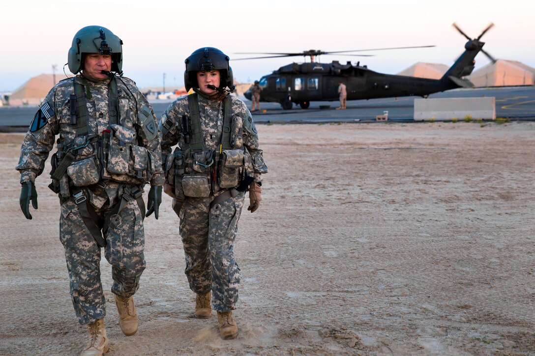 U.S. Army Sgt. 1st Class Ed Light, left, and U.S. Army 1st Lt. Kelly Carbary stretch their legs as their UH-60 Black Hawk helicopter is fueled by soldiers after a flight mission in Arifjan, Kuwait, Feb. 6, 2014. Carbary, a pilot, and Light, a crew chief, are assigned to the Michigan Army National Guard's 3rd Battalion, 238th General Support Aviation Battalion, and the soldiers are assigned to the 642nd Aviation Support Battalion.