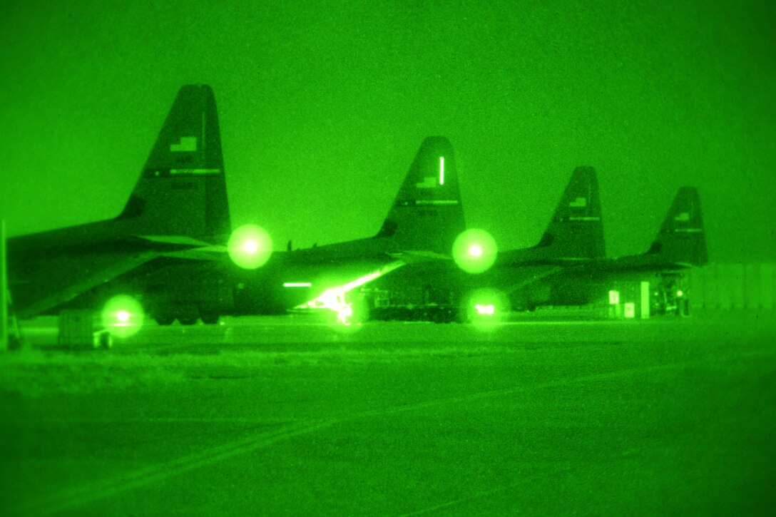 As seen through a night-vision device, U.S. airmen load C-130J Super Hercules aircraft for a night mission while parked on Bagram Airfield, Afghanistan, Feb. 11, 2014.