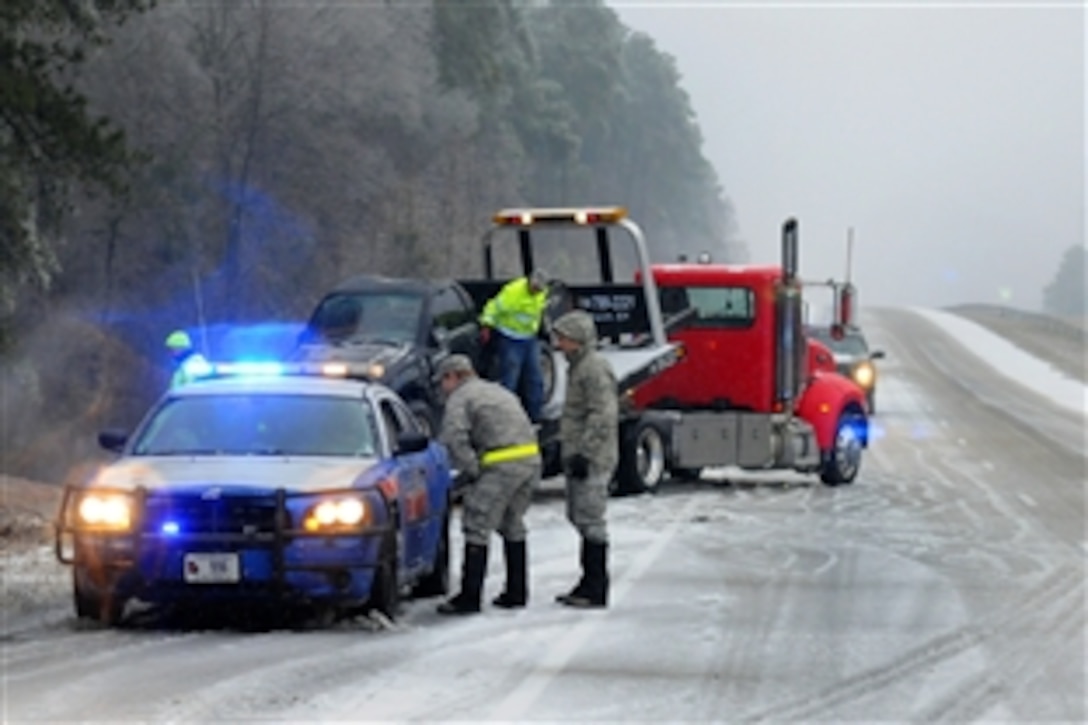 Air Force Maj. Nicholas Anthony, left, speaks with a Georgia State Patrol officer at the scene recovering a vehicle that slid off the road along Interstate 20 while providing emergency service and support to civil authorities and to residents during a winter storm, Augusta, Ga., Feb. 12, 2014. Anthony is a flight commander for Georgia National Guard's 165th Air Support Operations Squadron, Savannah, Ga.