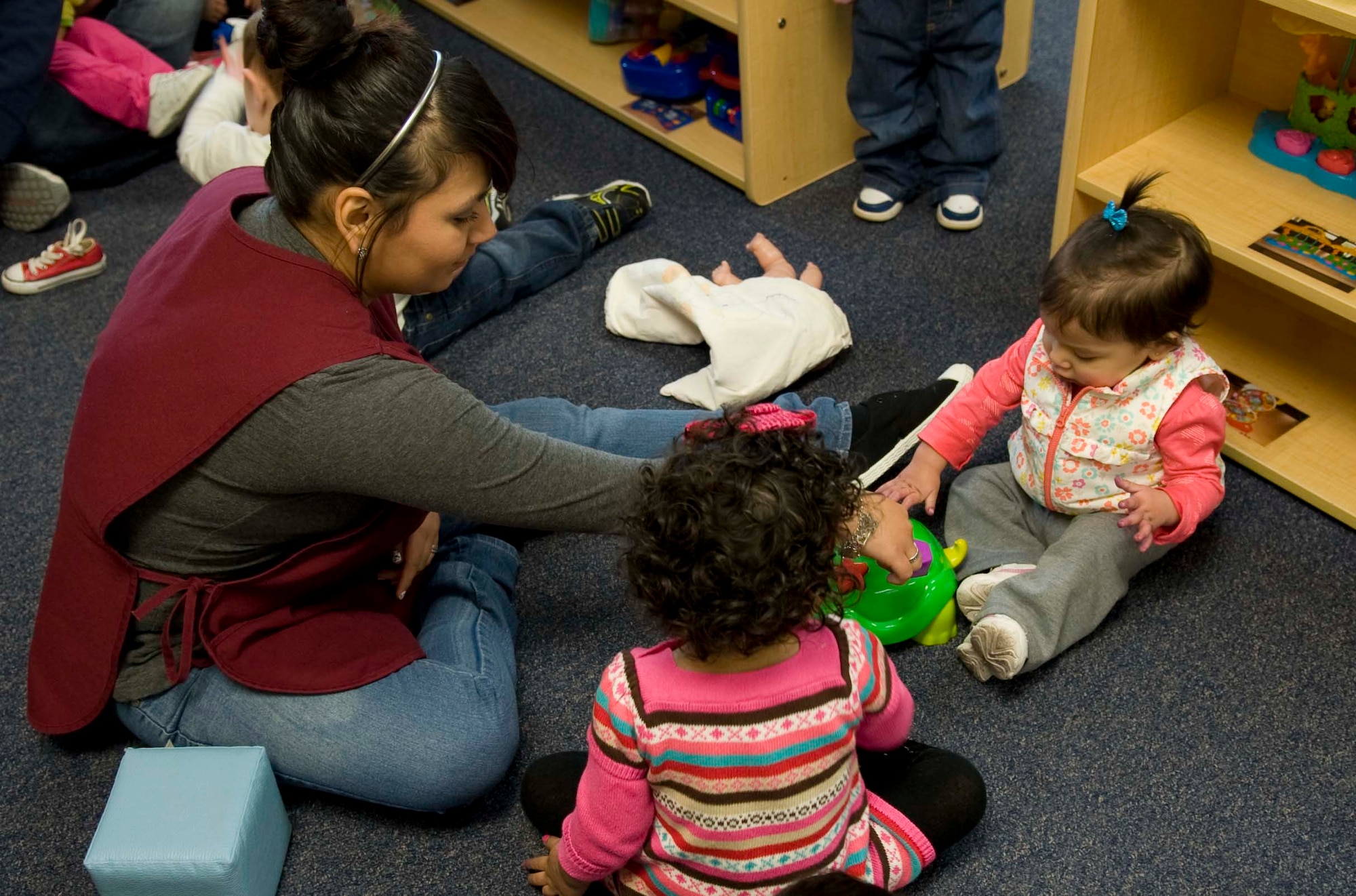 Francise Gonzales, Dyess Child Development Center caregiver, plays with two toddlers she oversees, Aubrey and Isabella Feb. 5, 2014, at Dyess Air Force Base, Texas. The CDC was recently recognized for their hard work and dedication throughout 2013 by being awarded best in Air Combat Command for the second year in a row for their Child Development Program. (U.S. Air Force photo by Airman 1st Class Kylsee Wisseman/Released)