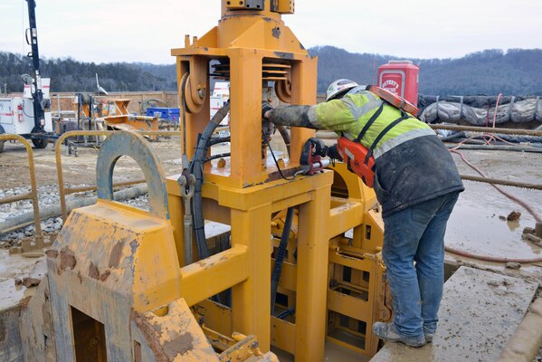 A worker for the Bauer Foundation Corporation inspects a large clamshell excavator for maintenance at the ongoing foundation rehabilitation project at Center Hill Dam.    