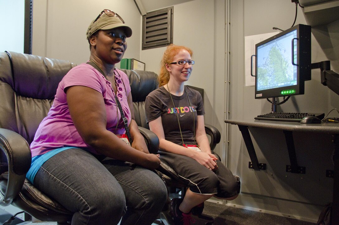 Ericka Barry (left) and Alicia Terwilliger see the inside of a CH-53E Super Stallion flight simulator at building 6789 during the "A Day in the boots of a MAG-nificent Marine or Sailor" event, Feb. 12, 2014.