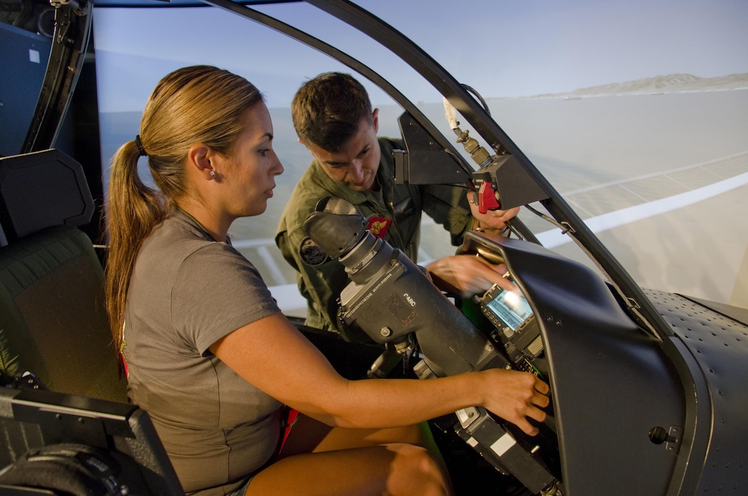 Monica Morales listens to instructions from Capt. Justin Campbell, the operations officer of Marine Aviation Training Support Squadron, before trying out the AH-1W Super Cobra flight simulator at building 6789 during the "A Day in the Boots of a MAG-nificent Marine or Sailor" event, Feb. 12, 2014. 