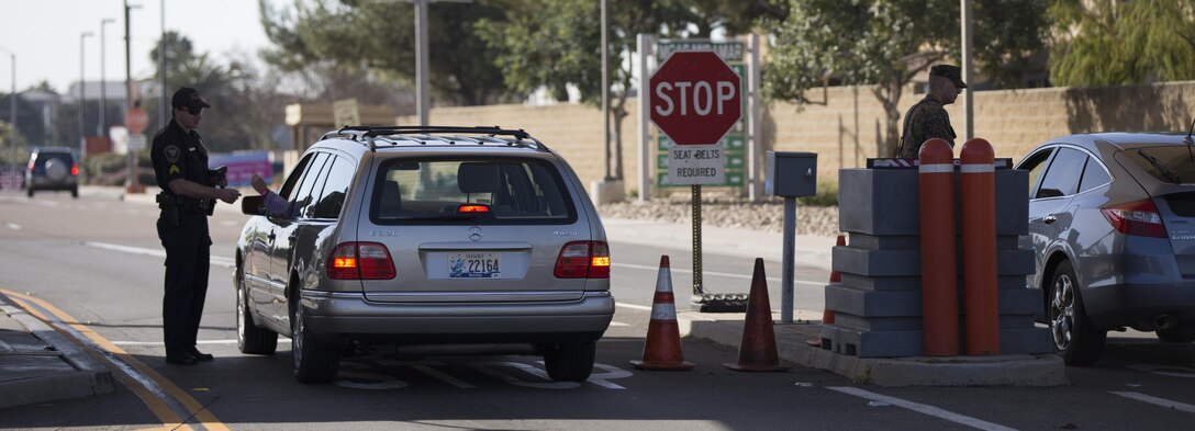 A Marine and Marine Corps civilian police officer work together checking cars at the north gate of Marine Corps Air Station Miramar, Calif., Feb. 11. Marine Corps civilian police officers work with Marines to assist in the security and law enforcement workload aboard the installation.