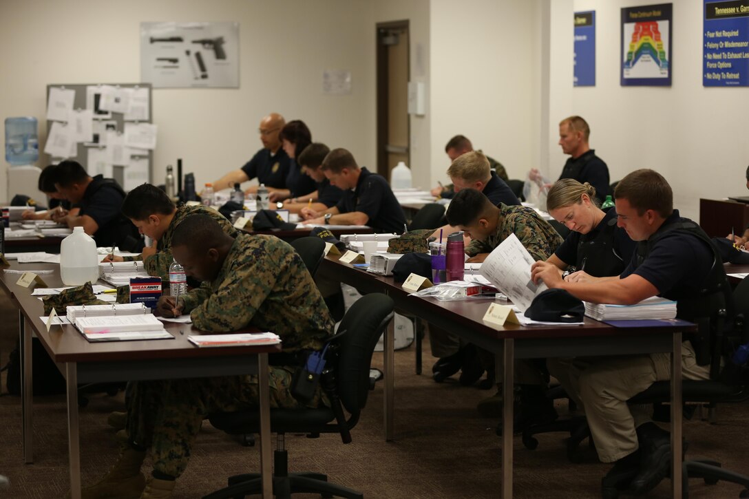 Marine and civilian students review their work together in the same classroom aboard Marine Corps Air Station Miramar, Calif., Feb. 11. Both groups went through the same training at the Marine Corps Police Academy West: Marines for follow-on training and civilian students for certification to become Marine Corps civilian police officers.