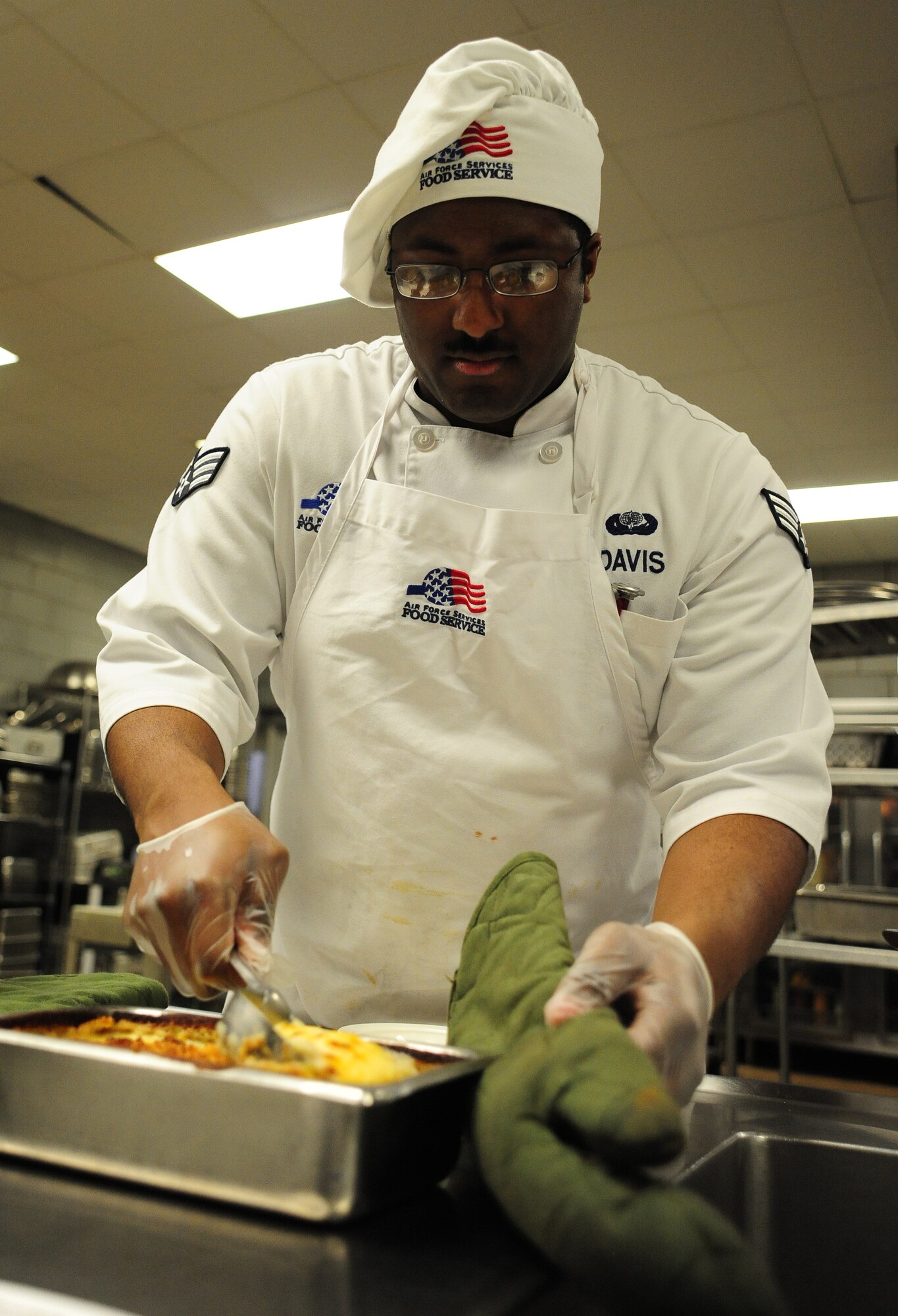 Senior Airman Janoy Davis, 509th Force Support Squadron food services specialist, prepares Au Gratin potatoes during a Hennessy Team inspection at the Ozark Inn dining facility at Whiteman Air Force Base, Mo., Feb. 6, 2014. Davis prepared the food as part of “A Day in the Life of a Food Service Airmen” where the Hennessy Team evaluators toured the dining facility kitchen and were given baking and cooking demonstrations by food services specialists. (U.S. Air Force photo by Staff Sgt. Nick Wilson/Released)