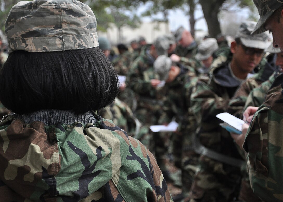 An Airman overlooks a group preparing for a training scenario Feb. 13 at Heritage Park. They wear Mission-Oriented Protective Posture equipment as part of a Combat Airman Skills Evaluation exercise. (U.S Air Force photo by Airman 1st Class Solomon Cook)