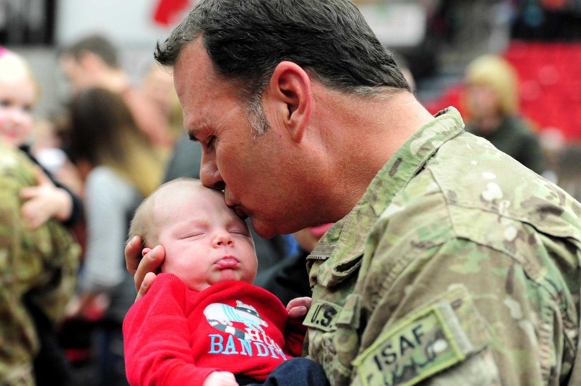 U.S. Army Sgt. 1st Class Ed Borgstadt, 1-135th Attack Reconnaissance Battalion operations NCO in charge, kisses his three-week-old grandson for the first time following the unit's welcome-home ceremony at the University of Central Missouri 
in Warrensburg, Mo., Feb. 9, 2014. Borgstadt returned home after a year-long deployment to Afghanistan in support of Operation Enduring Freedom. (U.S. Air Force photo by Staff Sgt. Nick Wilson/Released)