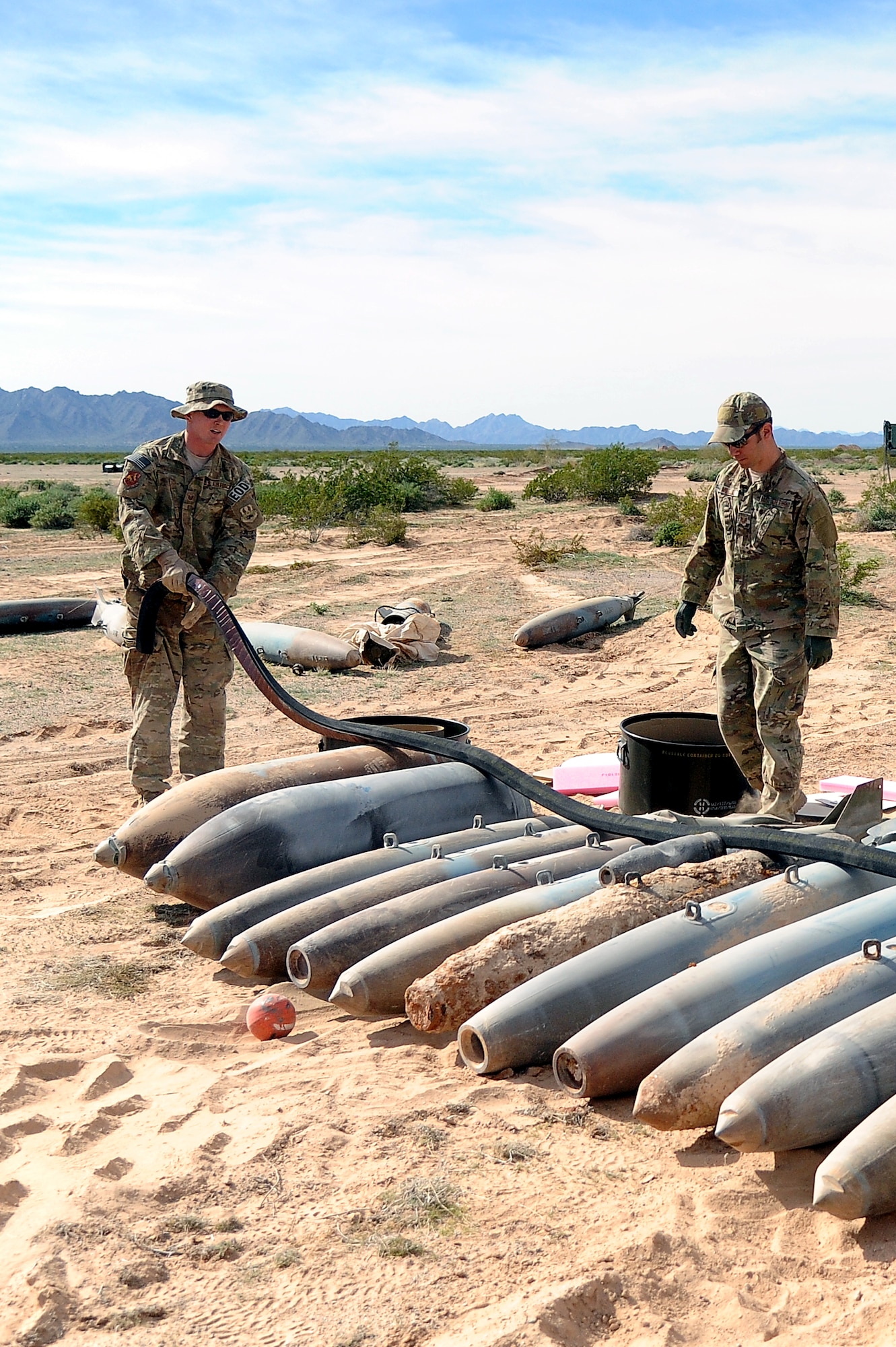 Staff Sgt. Zachary Holschuh, left, 56th Civil Engineer Squadron Explosive Ordnance Disposal team leader, and Tech. Sgt. Christopher Mueller, 56th CES EOD team leader, lay out explosive cutting tape across undetonated ordnance Jan. 30 at the BMGR. The ECT is used to cut through empty and concrete ordnance. (U.S. Air Force photo/Airman 1st Class Pedro Mota)