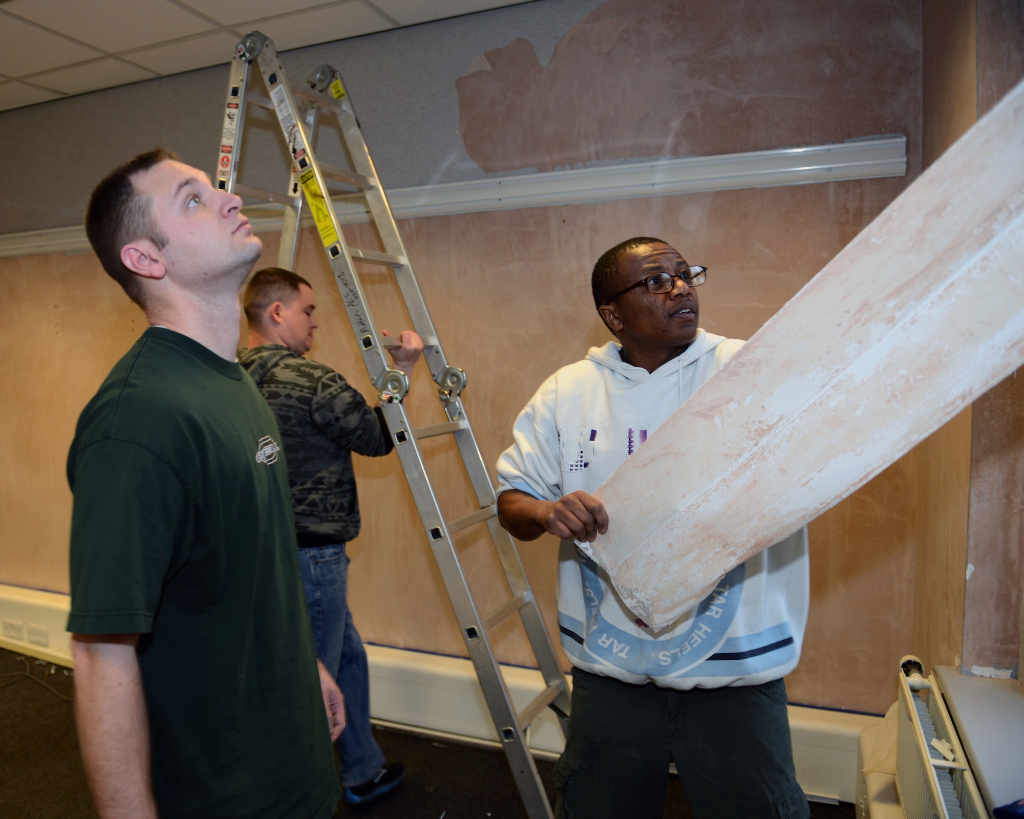 Team Mildenhall members remove wallpaper Feb. 14, 2014, in the 352nd Special Operations Group, Flight Room at Mathies Airman Leadership School on RAF Feltwell, England. The Team Mildenhall Top 3 organized a volunteer force to redecorate two classrooms in the schoolhouse. Volunteers repainted both classrooms, and added historical memorabilia to the the 100th Air Refueling Wing, Flight Room. (U.S. Air Force photo by Airman 1st Class Preston Webb/Released)