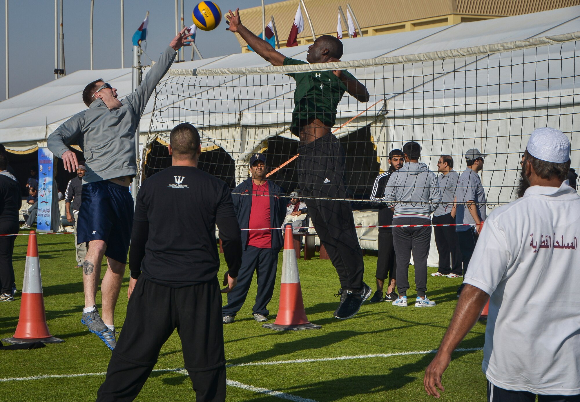 Service members and Qatar Emiri air force members play a friendly game of volleyball during Qatar National Sports Day at Al Udeid Air Base, Qatar, Feb. 11, 2014. For the first time more than 100 Airmen, Sailors, Soldiers, Marines and civilians were invited to participate in the event to play basketball, soccer and volleyball with their host nation counter parts. The Qatar National Sports Day is an initiative adopted in 2011 by the current Emir, Sheikh Tamim bin Hamad Al Thani, to further embed sporting values into the nation's culture and inspire people to be healthy and engage in physical activities. (U.S. Air Force photo/Senior Airman Jared Trimarchi)