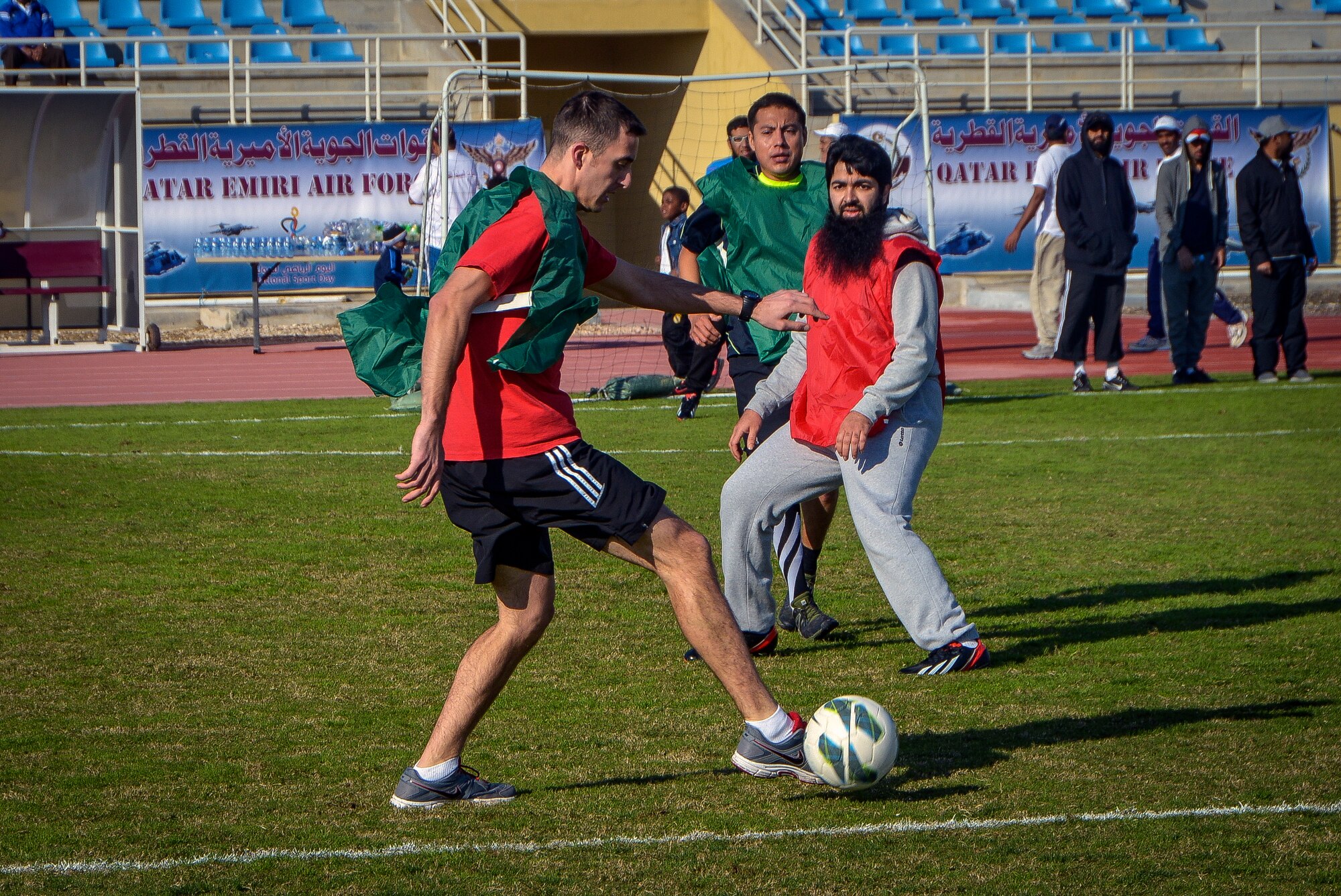 Service members and Qatar Emiri air force members play a friendly game of soccer during Qatar National Sports Day at Al Udeid Air Base, Qatar, Feb. 11, 2014. For the first time more than 100 Airmen, Sailors, Soldiers, Marines and civilians were invited to participate in the event to play basketball, soccer and volleyball with their host nation counter parts. The Qatar National Sports Day is an initiative adopted in 2011 by the current Emir, Sheikh Tamim bin Hamad Al Thani, to further embed sporting values into the nation's culture and inspire people to be healthy and engage in physical activities. (U.S. Air Force photo/Senior Airman Jared Trimarchi)
