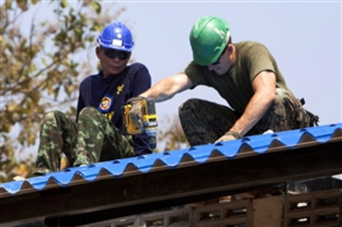 U.S. Marine Cpl. Jerad Miles and Thai soldier Wiboon Phosri, left, attach roofing tiles during exercise Cobra Gold 2014 at Wattatakian School in Phitsanulok, Thailand, Feb. 7, 2014. Miles is assigned to Company A, 9th Engineer Support Battalion, 3rd Marine Logistics Group, 3rd Marine Expeditionary Force. 