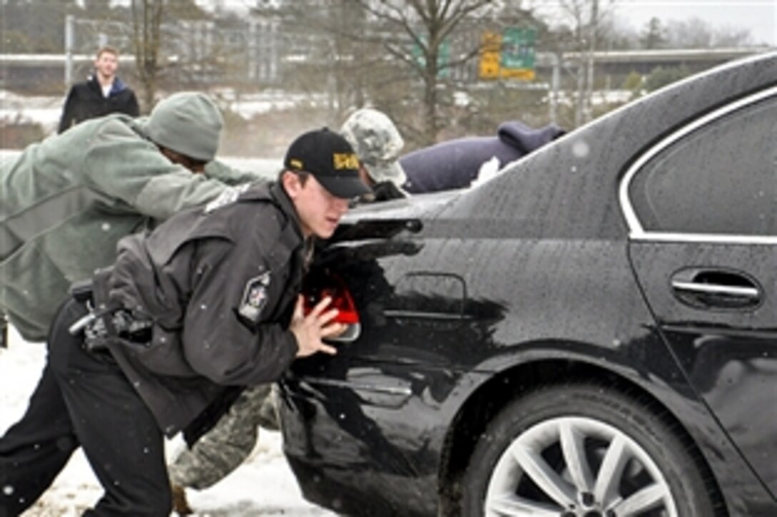 Army Pfc. Lorenzo Garrick and Wake County Sheriff's Office Deputy Erik Seda push a stranded motorist out of the ditch along an exit ramp in Raleigh, N.C., Feb. 13, 2014. The North Carolina National Guard has been assisting law enforcement agencies with their patrols throughout the state during and after a winter storm. Garrick is assigned to the 113th Sustainment Brigade.
