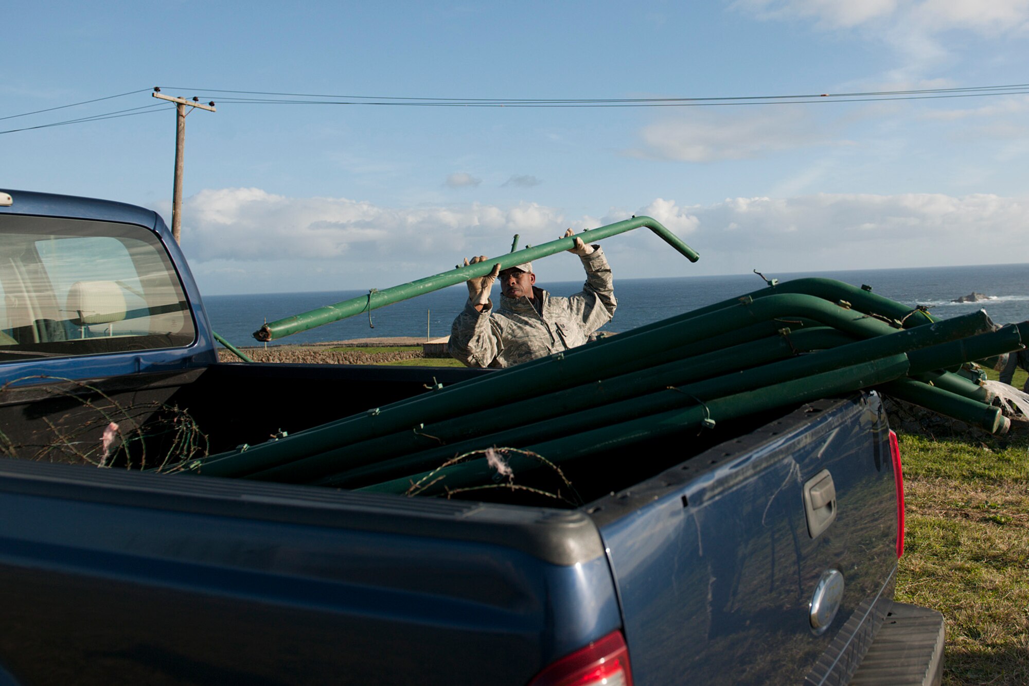 U.S. Air Force Airmen Tech. Sgt. Eric Wilson, 65th Civil Engineer Squadron heavy equipment operator, collects broken fence posts Feb. 15, 2014, at Lajes Field, Azores. Lajes Field was hit with a low pressure weather system Feb. 13, and strong winds caused damages to base facilities and military family housing. (U.S. Air Force photo by Tech. Sgt. Paul Villanueva II/Released)