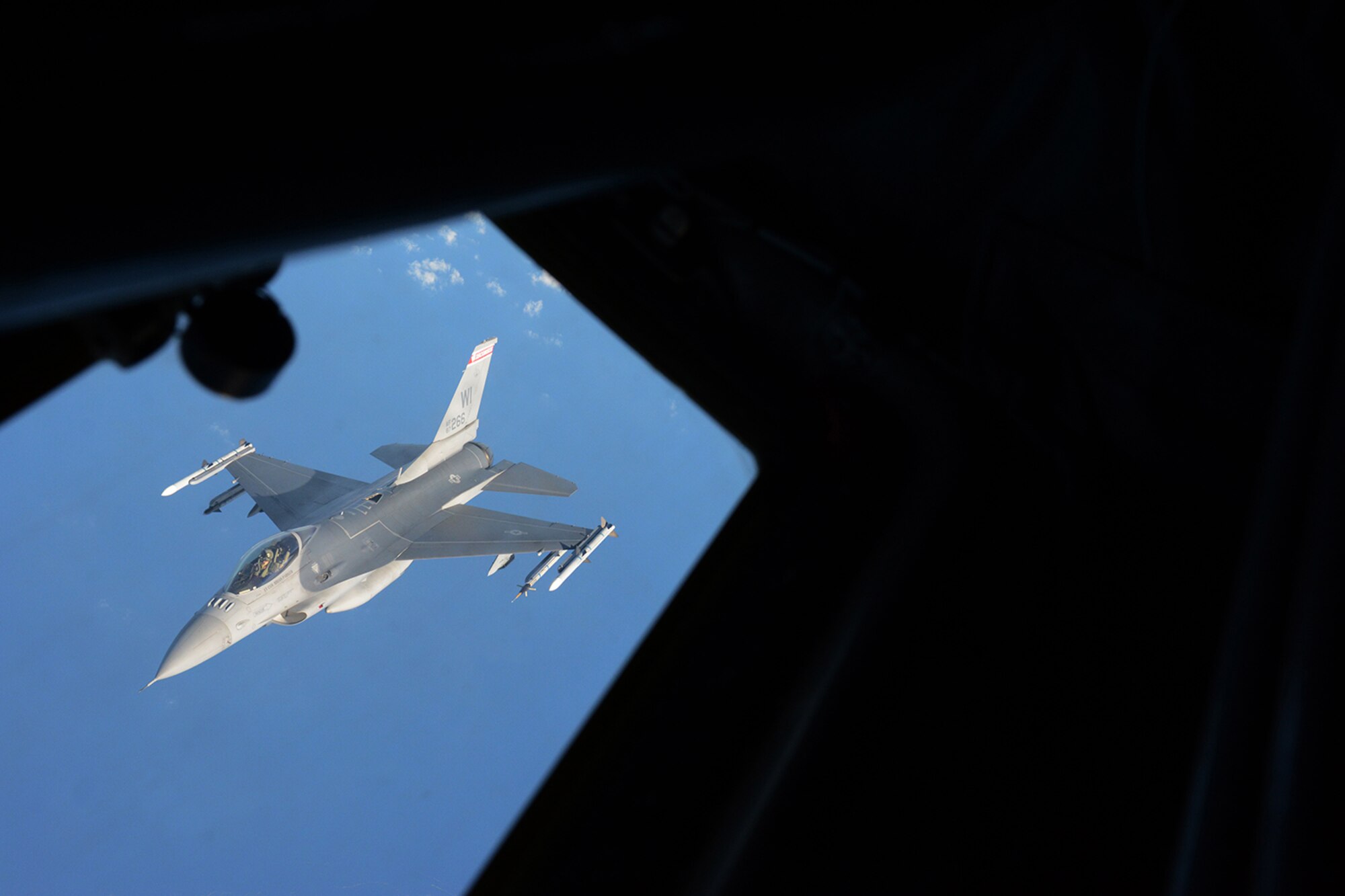 An Air National Guard F-16 Fighting Falcon assigned to the 115th Fighter Wing flies past the left boom operator's window of a KC-135 Stratotanker after refueling during a training exercise near Key West, Fla., Feb. 5, 2014. The 115th FW came to Key West in February to reduce the likelihood of flight cancelations due to weather. The deployment that lasted almost two weeks allowed the pilots to test their expertise against dissimilar aircraft. (Air National Guard photo by Senior Airman Andrea F. Liechti)