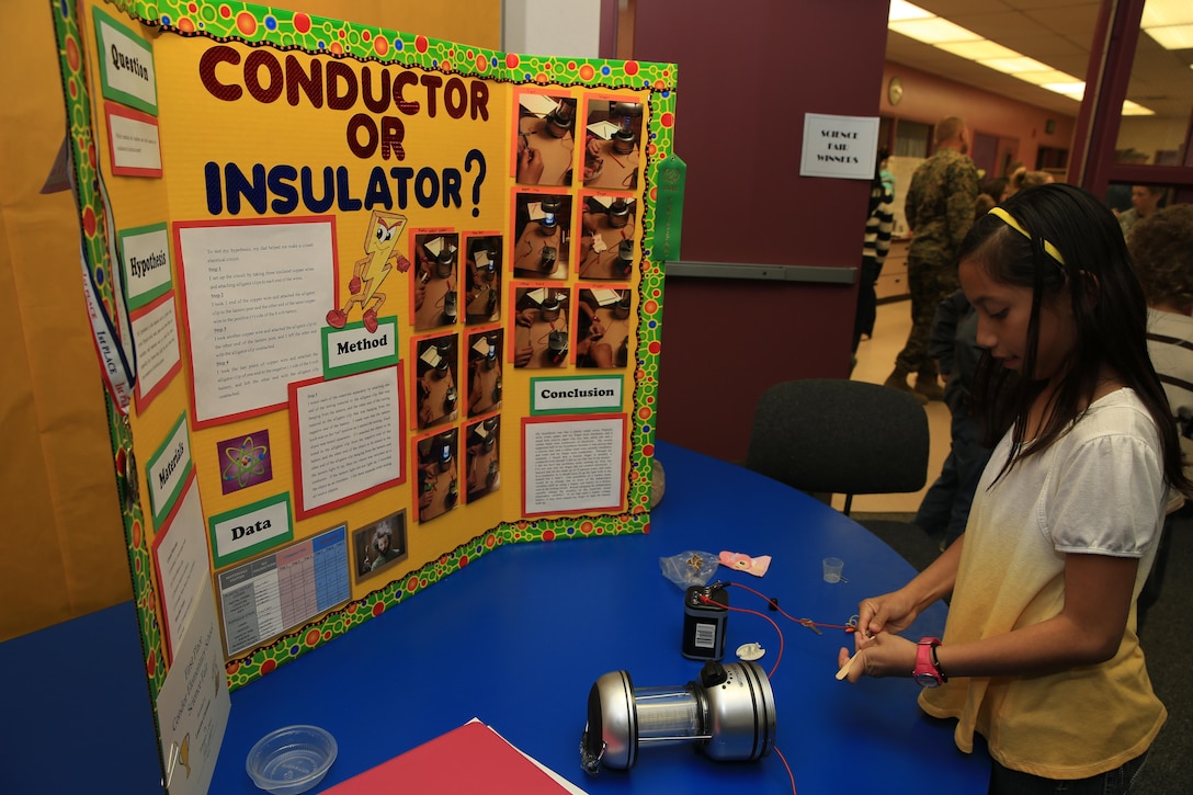 Lauren Guzman, 9, daughter of Gunnery Sgt. Steven Guzman, chief instructor, Advanced Electronics Course, Marine Corps Communication-Electronics School, sets up her project for display at Condor Elementary's Science Night, Feb. 5, 2014. Lauren's project involved completing a circuit with objects that are conductors of electricity to power a lamp.


