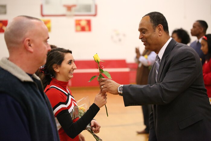 Michael Johnson, Quantico Middle/High School principal, hands a flower to Andrea, senior, during a senior recognition at the Quantico Middle/High School on Feb. 11, 2014. After the ceremony, the boys’ varsity basketball team won their last home game 77-65.