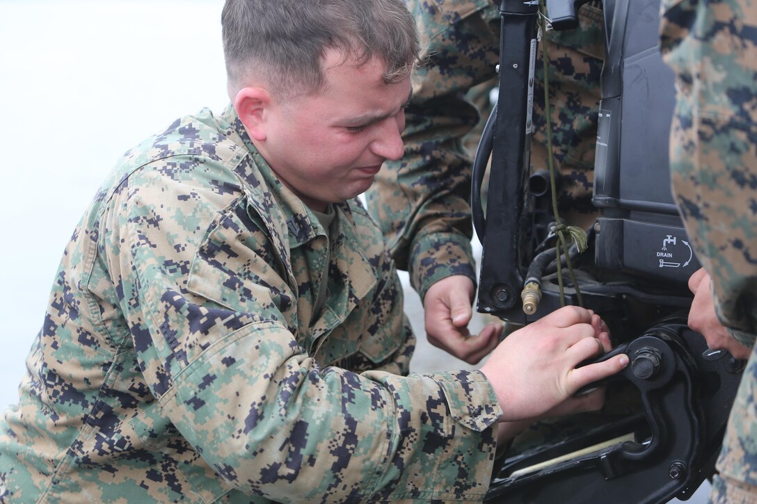 Corporal Hunter Paillou, cox swain with Operations Platoon, Boat Company, 7th Engineer Support Battalion, 1st Combat Logistics Regiment 1,1st Marine Logistics Group, prepares an engine to be mounted on a Combat Rubber Raiding Craft during training aboard Camp Pendleton, Calif., Feb. 11, 2014. The Marines are preparing for an exercise during which they will ferry equipment up and down the Colorado River giving them an opportunity to train in an arduous environment.