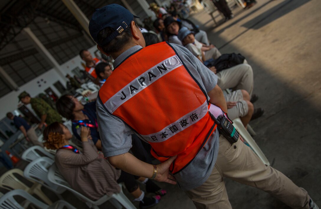 Japanese supporting staff member organizes the role playing evacuees at the Non-Combatant Evacuation Drill at Utaphao, Kingdom of Thailand Feb. 16 during Cobra Gold 2014.  Utilizing joint service and multinational training is vital to maintaining the readiness and interoperability of the Thai, U.S. and other participating military forces.