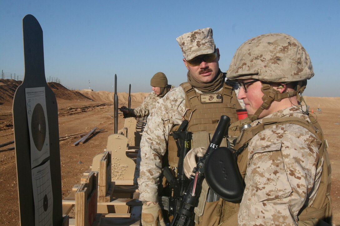 Staff Sergeant Michael Almendarez, center, food service mess chief, Marine Expeditionary Brigade - Afghanistan, speaks with Lance Cpl. Shane Pollard, right, food service specialist, about his rifle adjustments after he shot rounds at his target during a live-fire range exercise that took place aboard Camp Leatherneck, Helmand province, Afghanistan, Feb. 11, 2014. The exercise was used to prepare Marines to respond to a hostile threat aboard the base should one arise.
