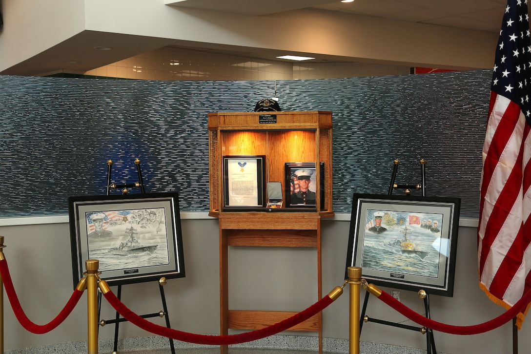 Portraits, paintings and the Medal of Honor citation of Cpl. Jason L. Dunham are presented during the dedication of the Cpl. Jason L. Dunham Memorial Mess Hall, Feb.18, 2014. The mess hall is dedicated to Dunham, who gallantly gave his life for his country, upholding the highest traditions of the Marine Corps.