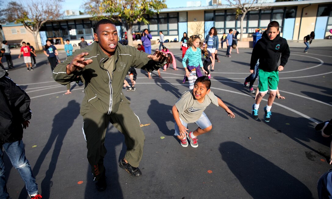 Cpl. Elijah Williams, a motor transportation mechanic with 1st Medical Battalion, 1st Marine Logistics Group, shows a student how to properly do a squat during a morning workout at Jefferson Elementary School Feb. 13, 2014. Marines with Combat Logistics Regiment 1 and 1st Medical Bn., volunteered their time to support more than 500 students in their new fitness program known as “Motion.” During their stay, Marines led various events such as push-ups, squats, soccer and basketball. 