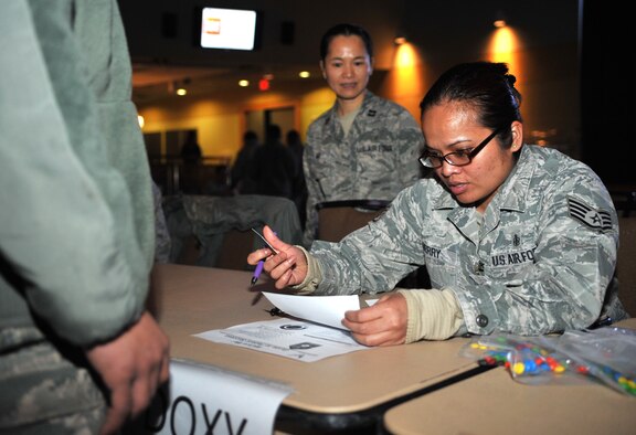 Staff Sgt. Judith Berry, 51st Medical Support Squadron pharmacy technician, examines an Airman’s paperwork to ensure he receives the correct simulated Anthrax prophylaxis during a point of distribution exercise at Osan Air Base, Republic of Korea, Feb. 7, 2014. The POD exercise tested the ability of the 51st Medical Group to screen and vaccinate base personnel in the event of a real-world public health emergency. (U.S. Air Force photo/Airman 1st Class Ashley J. Thum)