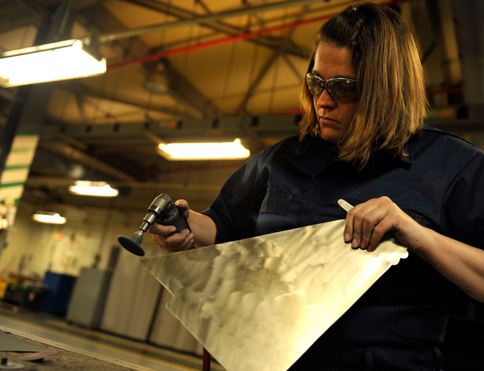 U.S. Air Force Staff Sgt. Tracy Powell, 18th Equipment Maintenance Squadron aircraft metals technology journeyman, polishes a metal part of an F-15 Eagle on Kadena Air Base, Japan, Feb. 14, 2014. 18th EMS operates 24/7 to provide metal work for all the aircraft assigned to Kadena. (U.S. Air Force photo by Naoto Anazawa)