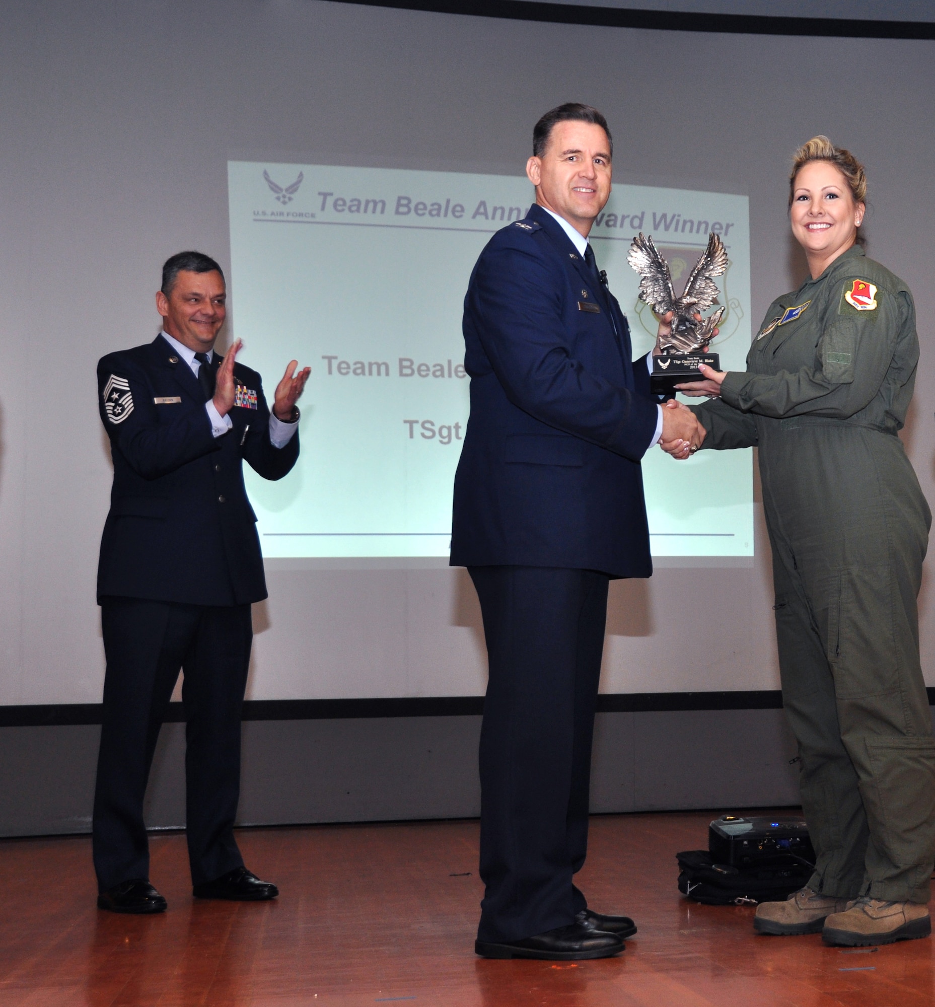 Annual award winner Tech. Sgt. Tilly Blake, 13th Reconnaissance Squadron, is recognized by Col. Kevin Cavanagh, 940th Wing commander, as Chief Master Sgt. Denny Brown applauds during a commander's call at the Unit Training Assembly, Feb. 9, on Beale Air Force Base, Calif. Blake, the wing's 2013 NCO of the Year, was also named the installation's Team Beale NCO of the Year. (U.S. Air Force photo/Tech. Sgt. Heather Skinkle)