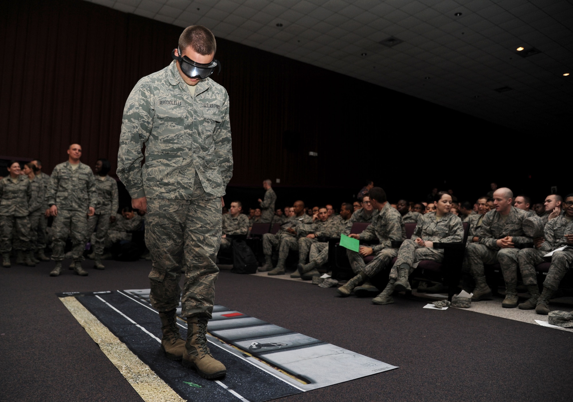 Airman Basic Matthew Rusciolelli, 338th Training Squadron, walks a line while wearing drunk goggles to simulate being intoxicated over the legal limit during a drunk busters program Feb. 14, 2014, at the Welch Theater, Keesler Air Force Base, Miss.  The drunk busters program illustrates the impact and effects of alcohol on a person’s senses and motor skills and is offered to those Airmen getting more responsibility through increase in transition privileges.   (U.S. Air Force photo by Kemberly Groue)