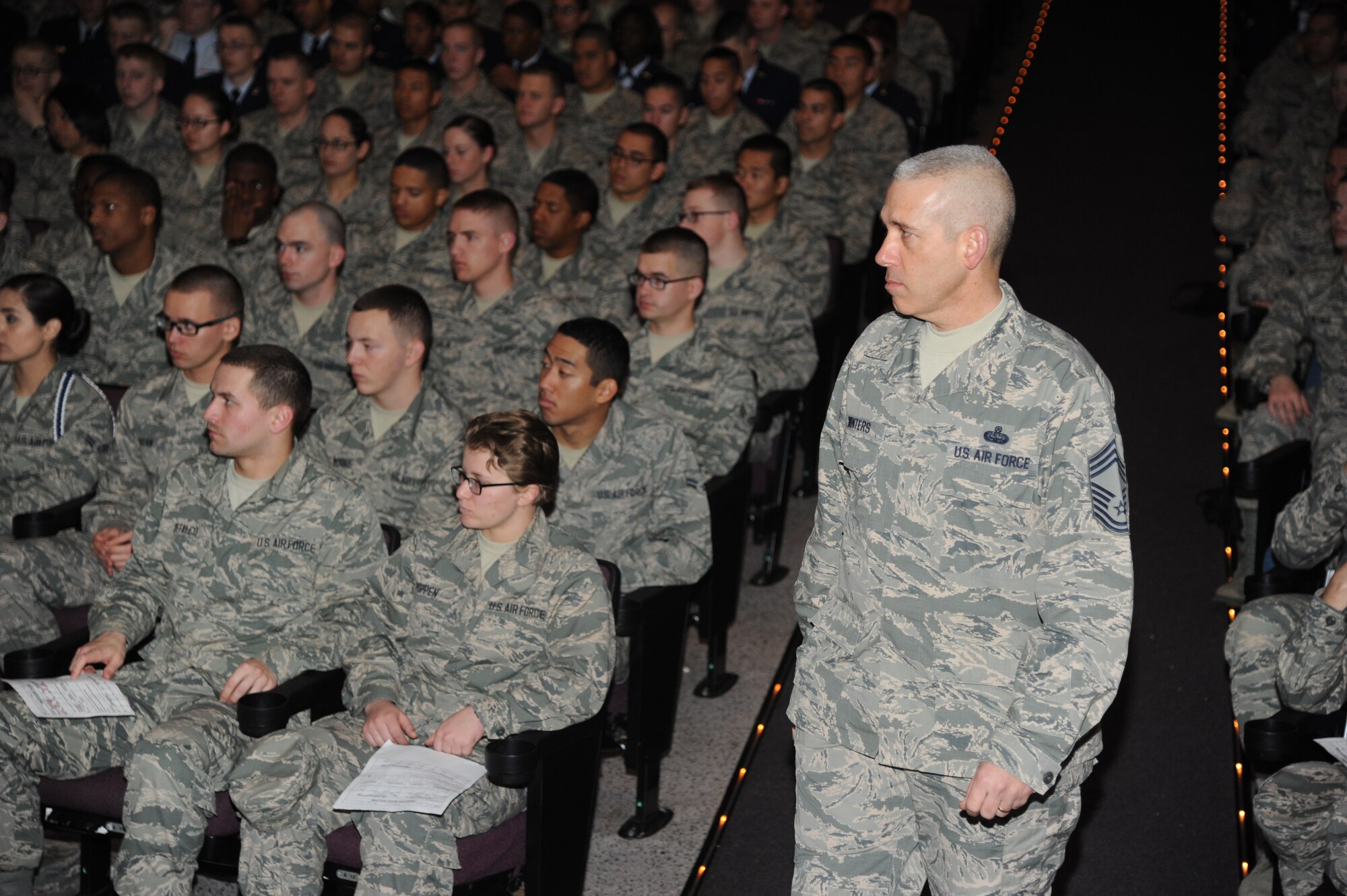 Chief Master Sgt. Robert Winters, 81st Training Group superintendent, watches over Keesler technical training students during a transition briefing Feb. 14, 2014, at the Welch Theater, Keesler Air Force Base, Miss.  The transition briefing is required for all Airmen who are transitioning up to the advanced transition phase (ATP) which allows them to go off base.  It helps reestablish expectations of proper conduct for those Airmen who have displayed proper Airmanship while at Keesler.  (U.S. Air Force photo by Kemberly Groue)