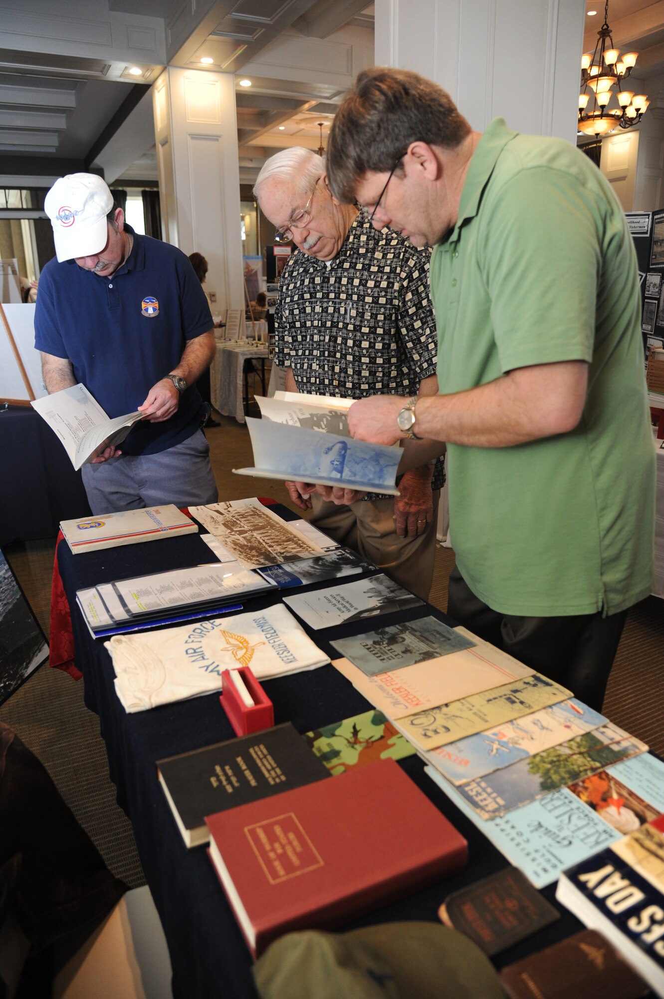 Kenneth J. Fountain, Biloxi native, (center), scans an old military photo as James LaChute, 338th Training Squadron, and Ken Dodd, 81st Training Wing historian, search through Keesler Air Force Base memorabilia for the location that the photo was taken during a Biloxi history week event Feb. 18, 2014, at the Biloxi, Mississippi Visitor Center.  The event was held from Feb. 16-18.  (U.S. Air Force photo by Kemberly Groue)