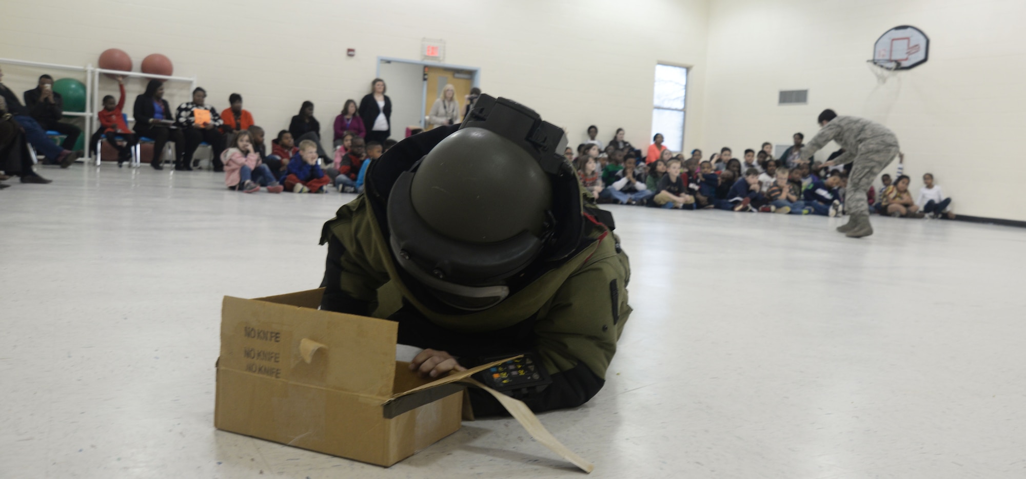 U.S. Air Force Senior Airman Christopher Brown, 20th Civil Engineer Squadron explosive ordinance disposal technician, demonstrates how a bomb would be diffused manually while wearing a bomb suit at Shaw Heights Elementary School, Feb. 10, 2014. U.S. Air Force 1st Lt. Nathan Demers, 20th CES EOD flight chief, and brown went to the school to teach the students about their different equipment and tools. (U.S. Air Force photo by Airman 1st Class Michael A. Cossaboom/Released) 
