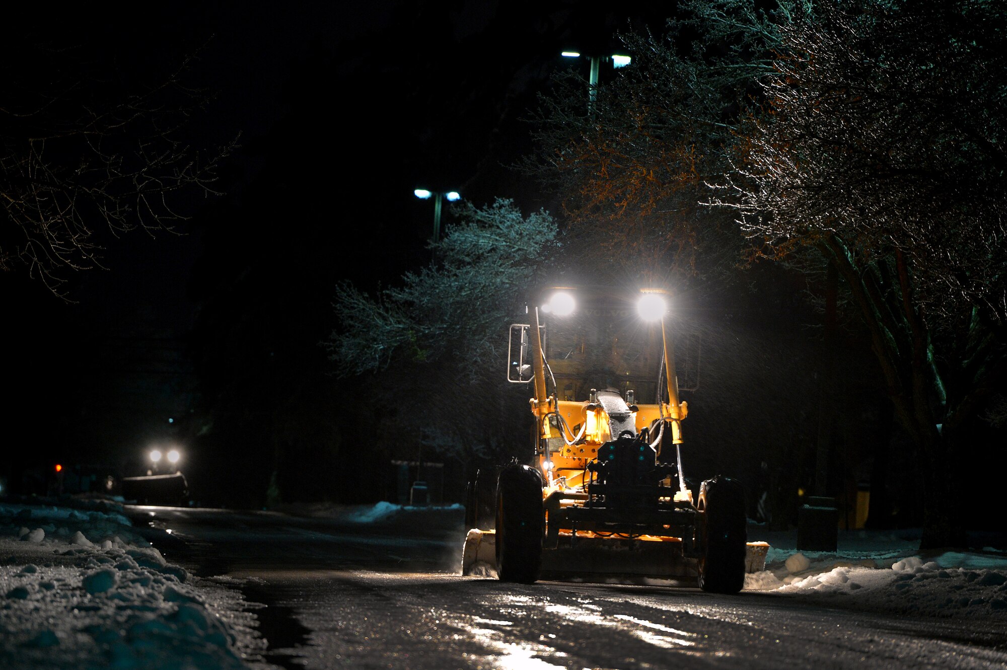 Team Shaw snow removal teams work into the night in order to clear Shaw’s main roads, Feb. 12, 2014, Shaw Air Force Base, S.C. As temperatures continued to drop during the night thick ice began to for over Shaw’s roads and sidewalks. As the inclement weather continues Team Shaw will continue to operate with "Mission Essential Personnel" only until further advised by the 20th Fighter Wing commander. Team Shaw personnel are urged to stay off the roads and use their best judgment if they do have to go out. (U.S. Air Force photo by Staff Sgt. Kenny Holston/Released)