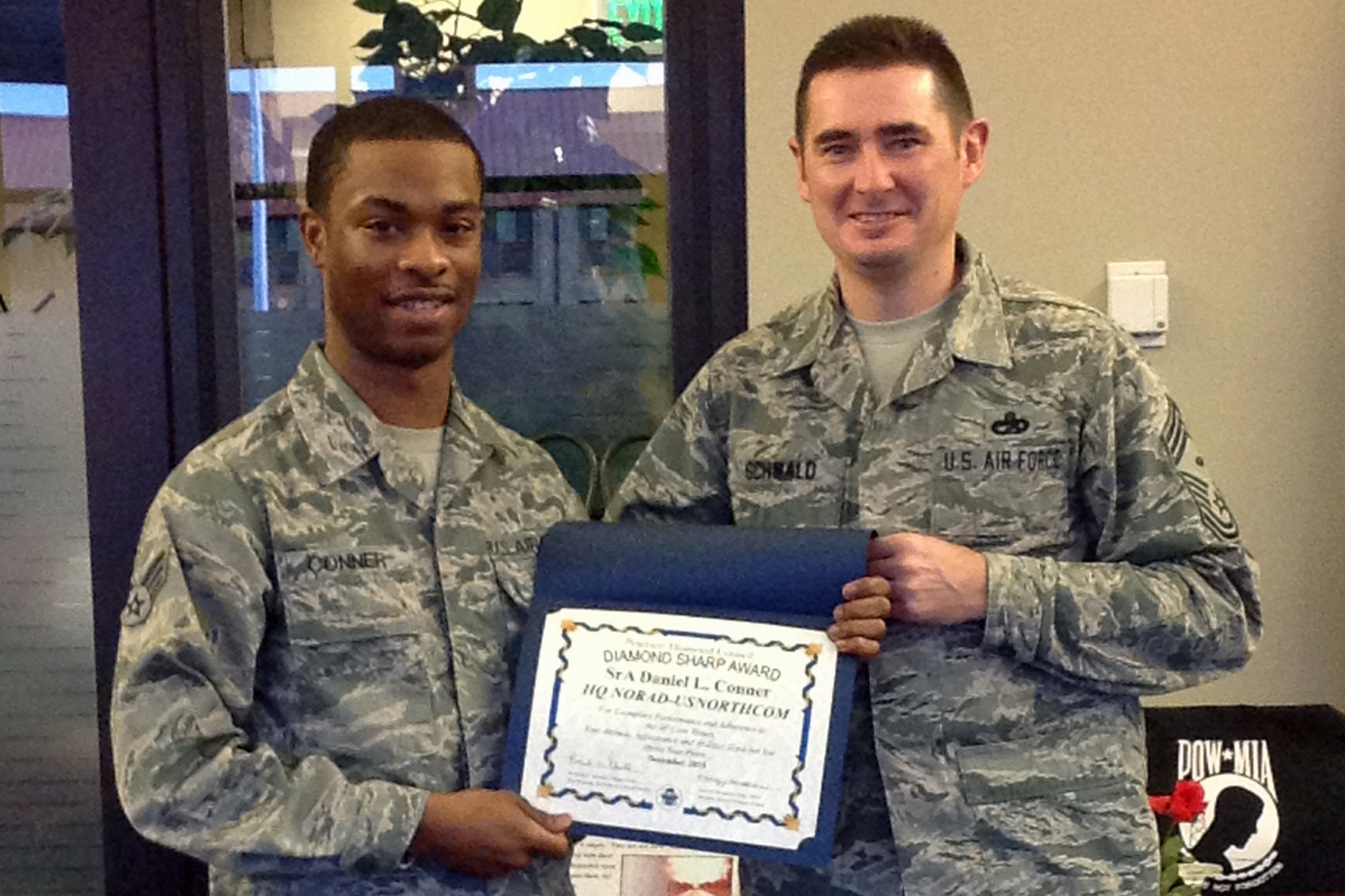 PETERSON AIR FORCE BASE, Colo. -- Senior Airman Daniel Conner (left), Headquarters, NORAD and USNORTHCOM, receives the Team Peterson First Sergeant Council Diamond Sharp award from Chief Master Sgt. Roderick Schwald, HQ NORAD and USNORTHCOM first sergeant. Conner is a knowledge operations manager, and performs myriad duties in support of the current operations center including records management, SharePoint content management, and evaluation and decorations coordination in support of more than 210 joint service and bi-national personnel. Conner is an active unit Joint Color Guard member, where he volunteered 25 hours off-duty time to seven community events, and was key in training 140 personnel which reduced preparation time requirements by two hours. (U.S. Air Force photo)
