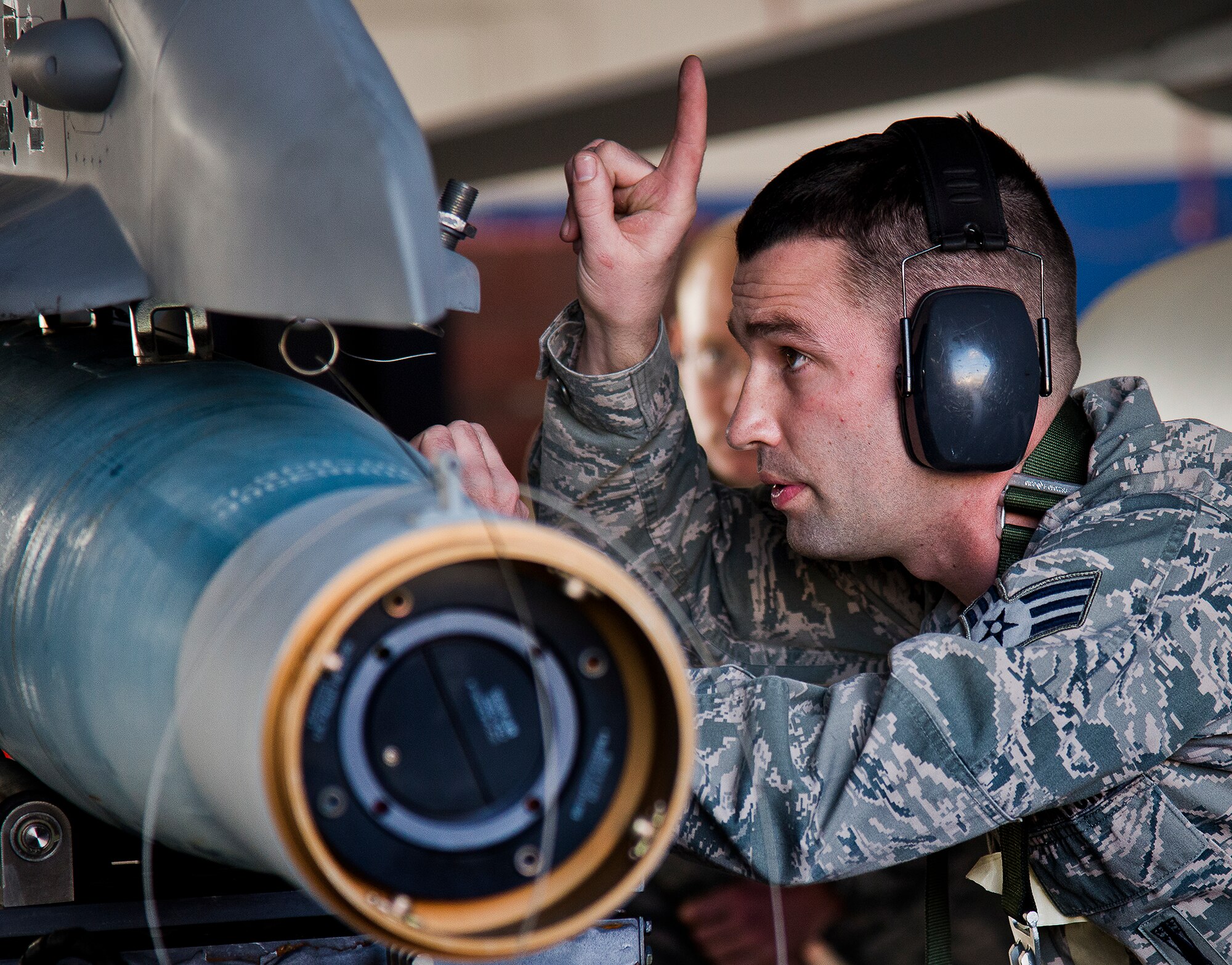 Senior Airman Thomas Schultz, of the 96th Aircraft Maintenance Squadron Blue, directs the weapons loader to lift the Guided Bomb Unit-12 up onto an F-16 Fighting Falcon during the annual weapons load crew of the year competition Feb. 14 at Eglin Air Force Base, Fla.  Teams from AMU Blue battled AMU Red in loading a GBU, AIM-9 and an AIM-120 on their respective aircraft.  The winners will be announced at the 96th Maintenance Group banquet.  (U.S. Air Force photo/Samuel King Jr.)