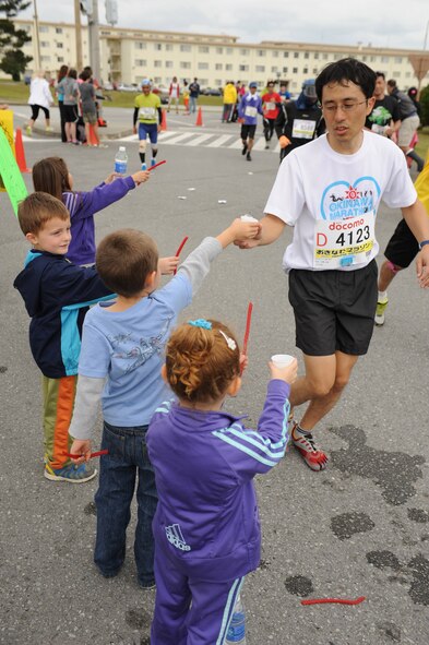 Children pass out water and candy to runners during the 2014 Okinawa Marathon on Kadena Air Base, Japan, Feb. 16, 2014. More than 11,000 participants signed up for the 2014 Okinawa Marathon with over 300 military participants running in the race and more than 500 volunteers assisting runners during the on-base portion. (U.S. Air Force photo by Airman 1st Class Keith James)