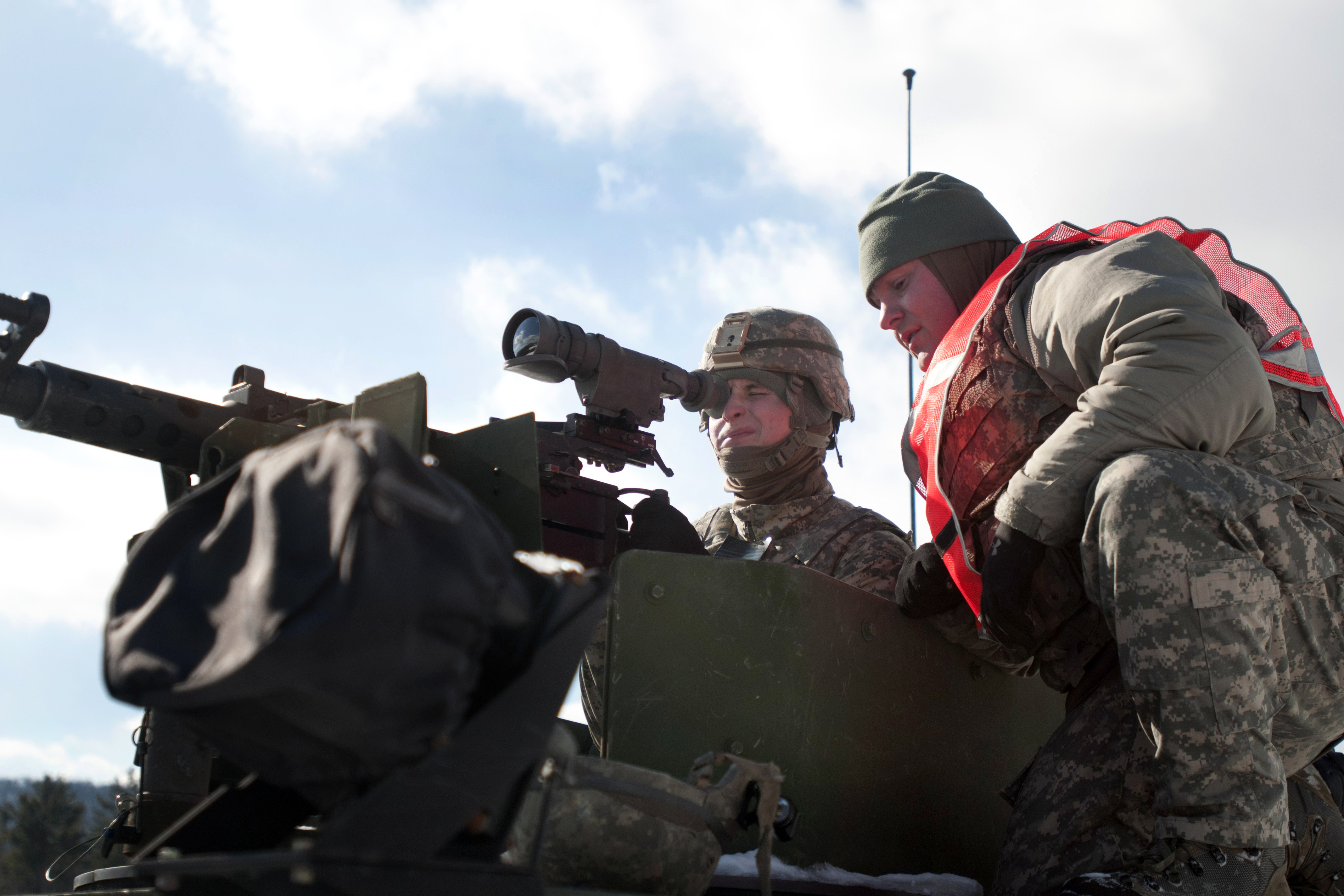 Army Spec. Zakery Hunt, left, adjusts sites on a .50-caliber M2 machine gun  with help